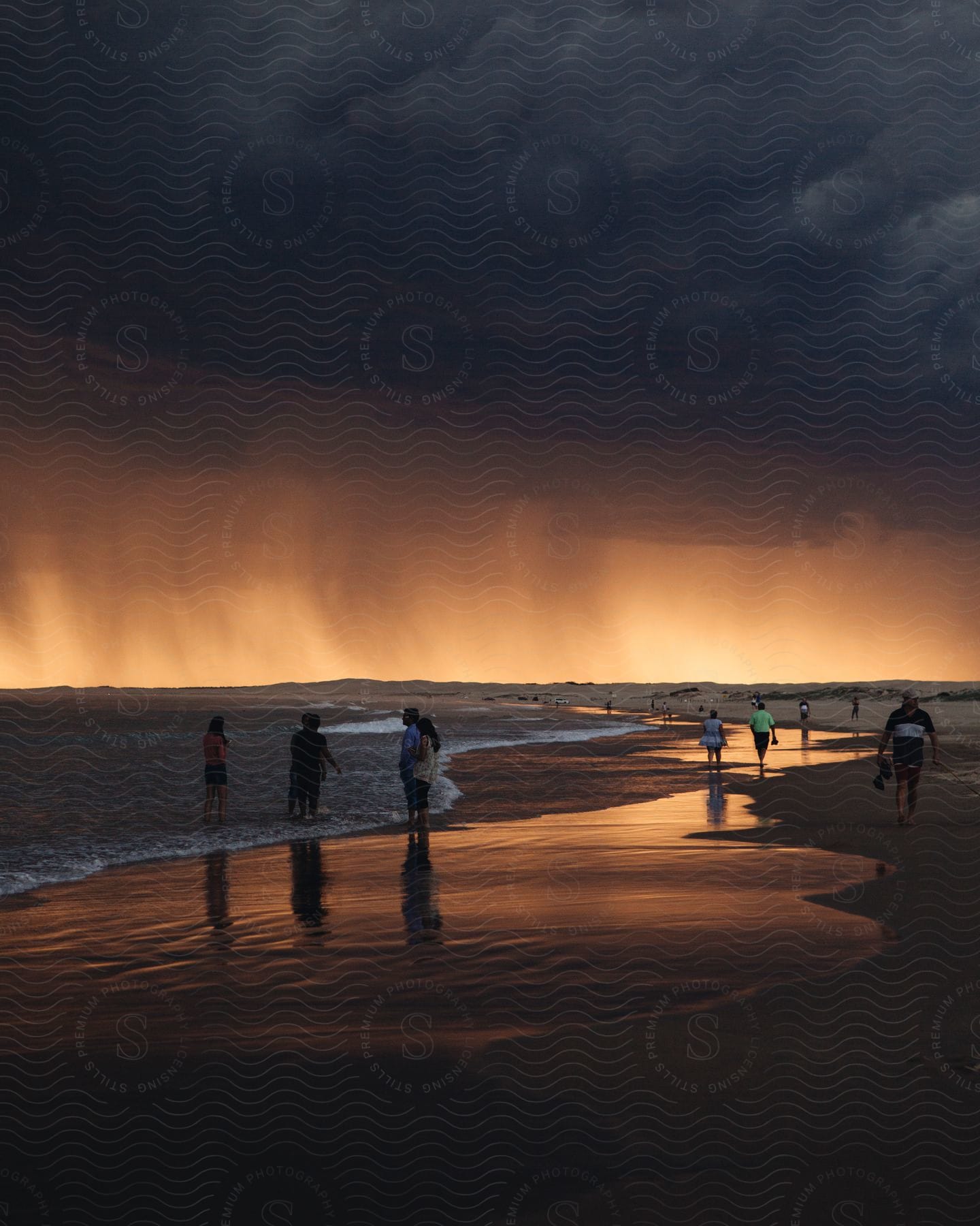 Landscape of a beach with people on the shore in an orange sky with black clouds and a late afternoon