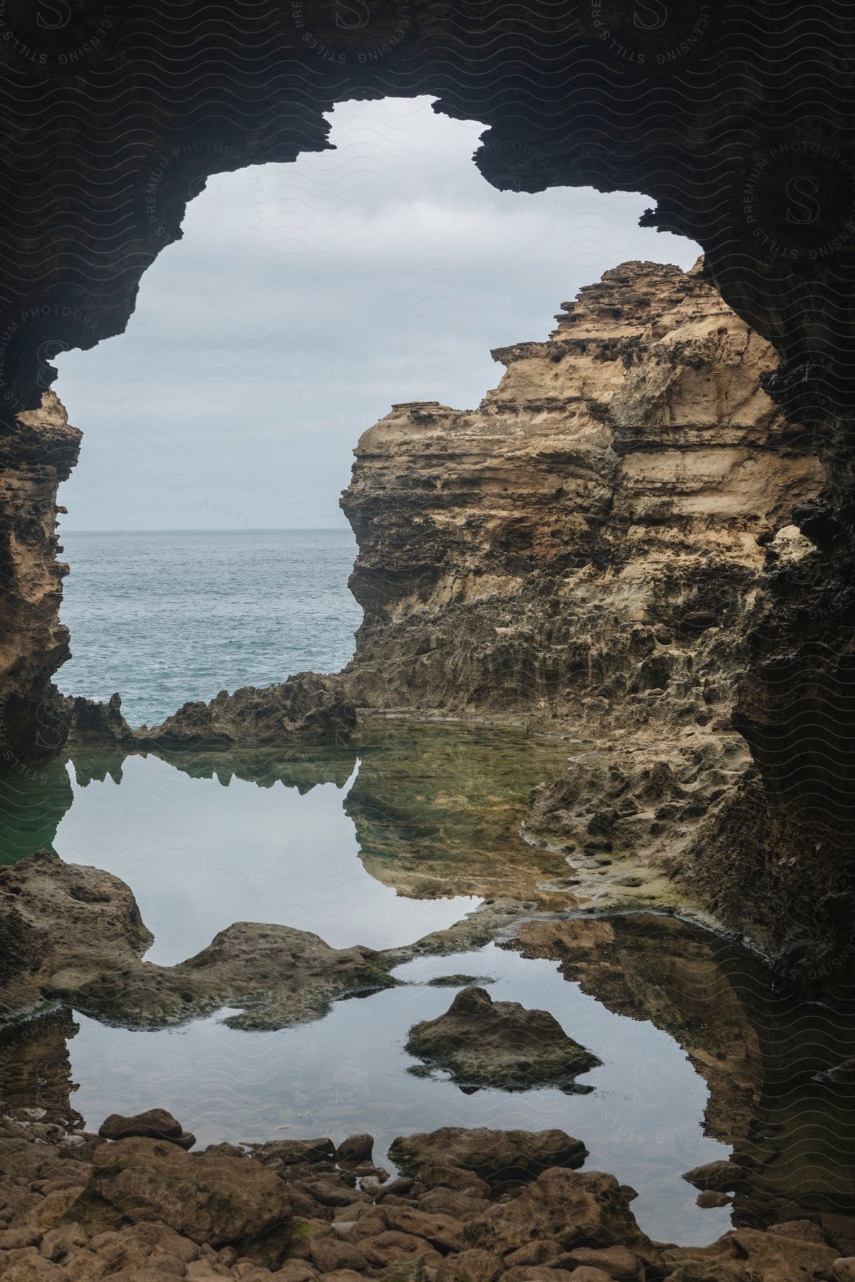 View through a cave along the coast with rock formations in the water