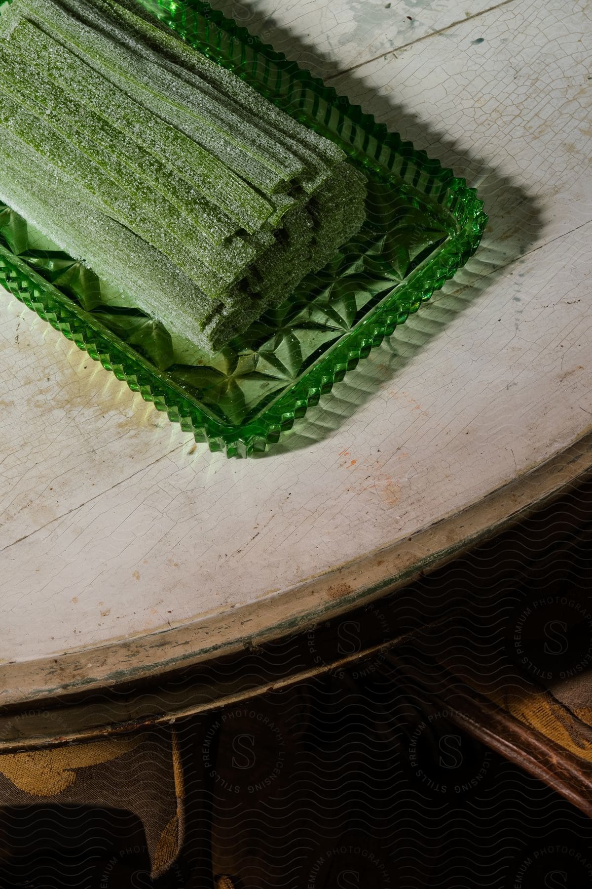 Long green strips of sugared dessert on a green glass serving plate atop a wooden table