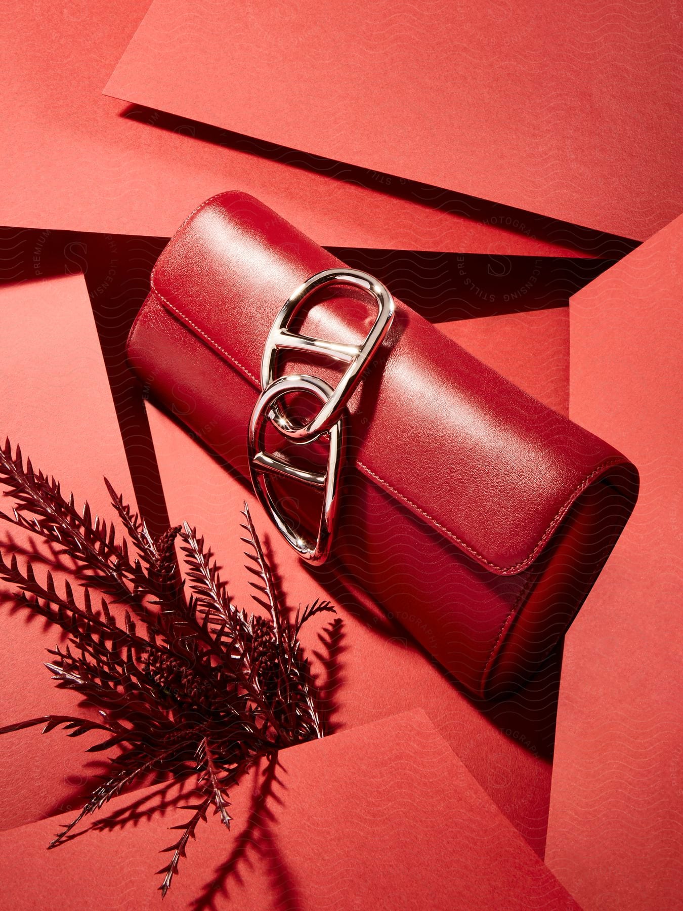 A red leather purse with silver buckles sits against a red background.