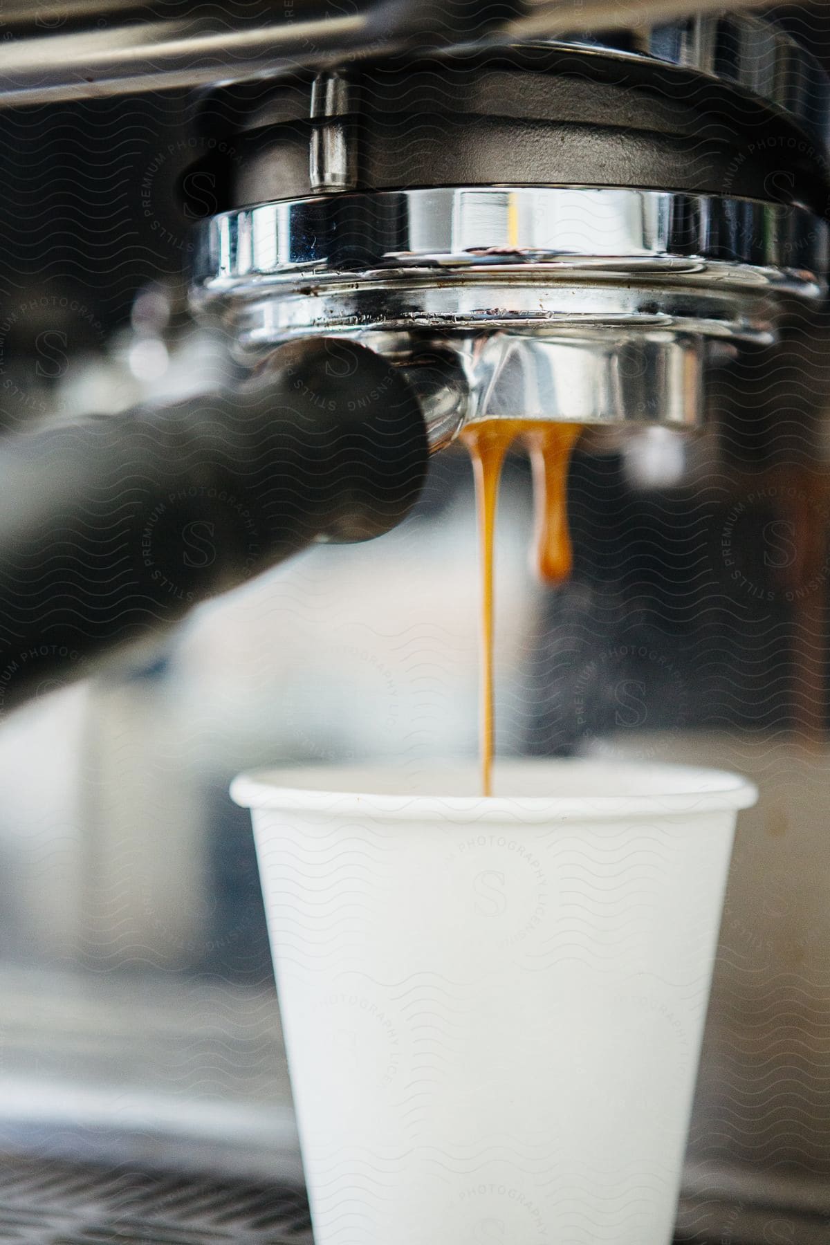 A coffee machine with a few drops falling into a white cup underneath