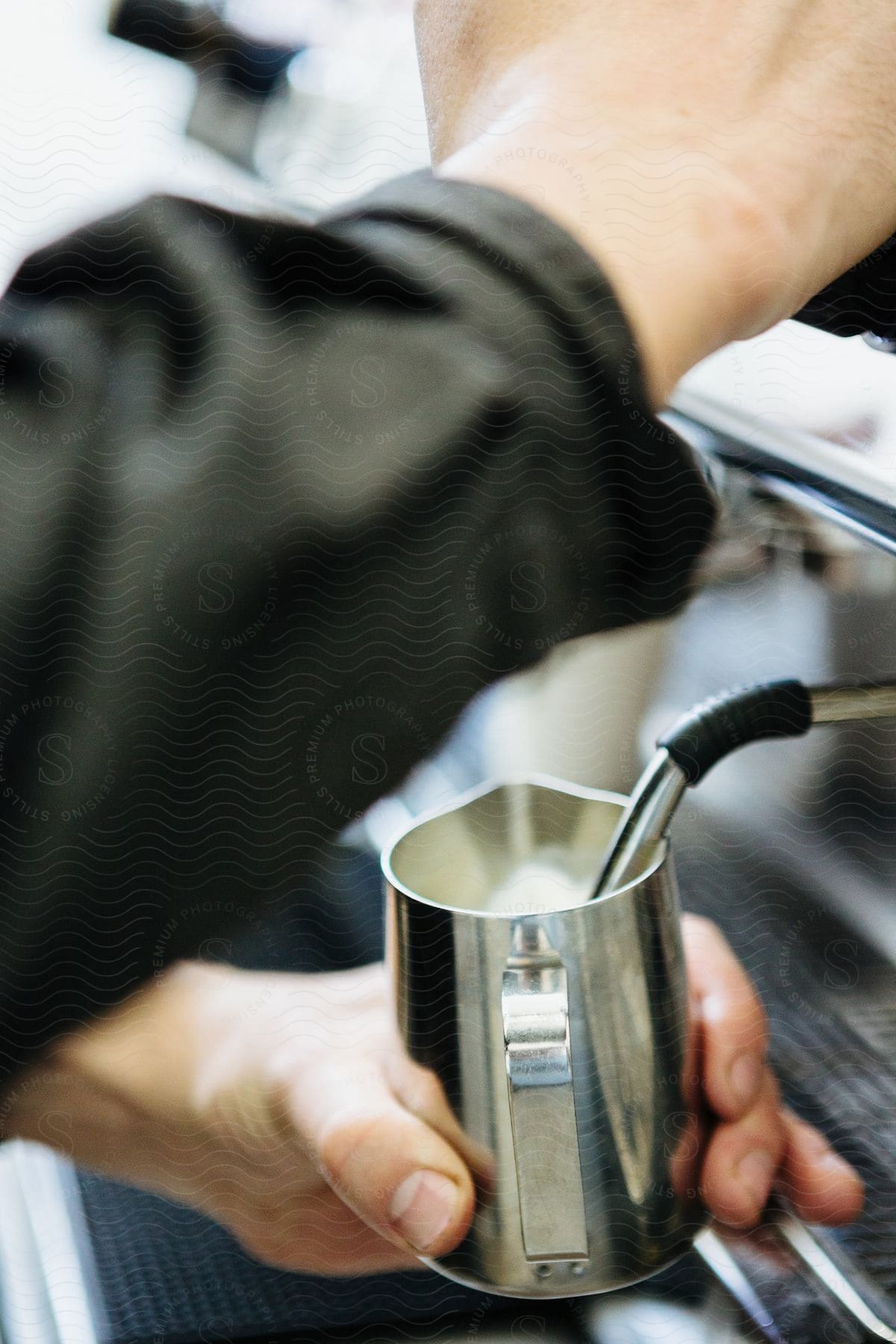 A close up view of someone frothing milk on an espresso machine.