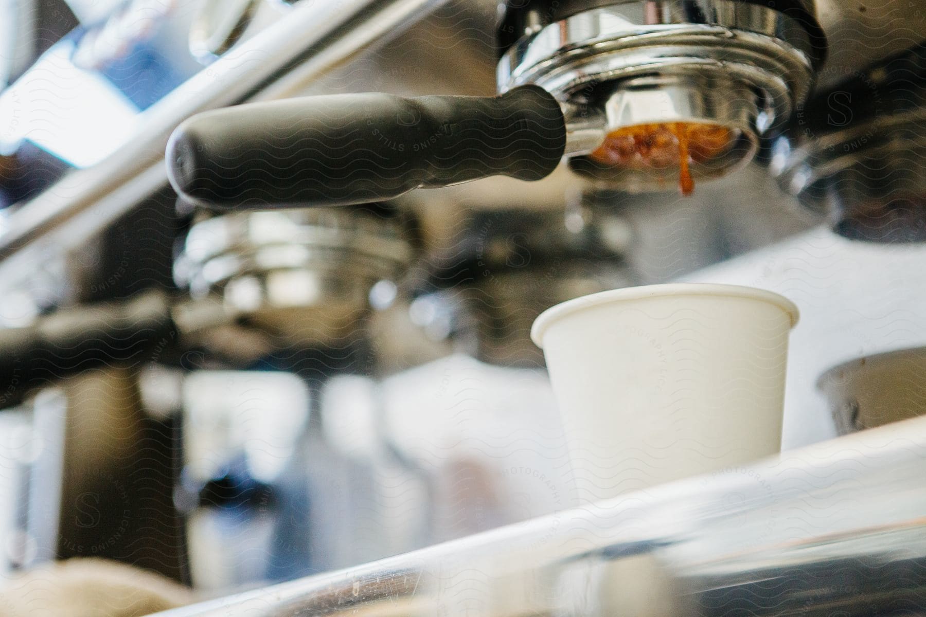 A coffee machine with a drop falling into a white cup underneath