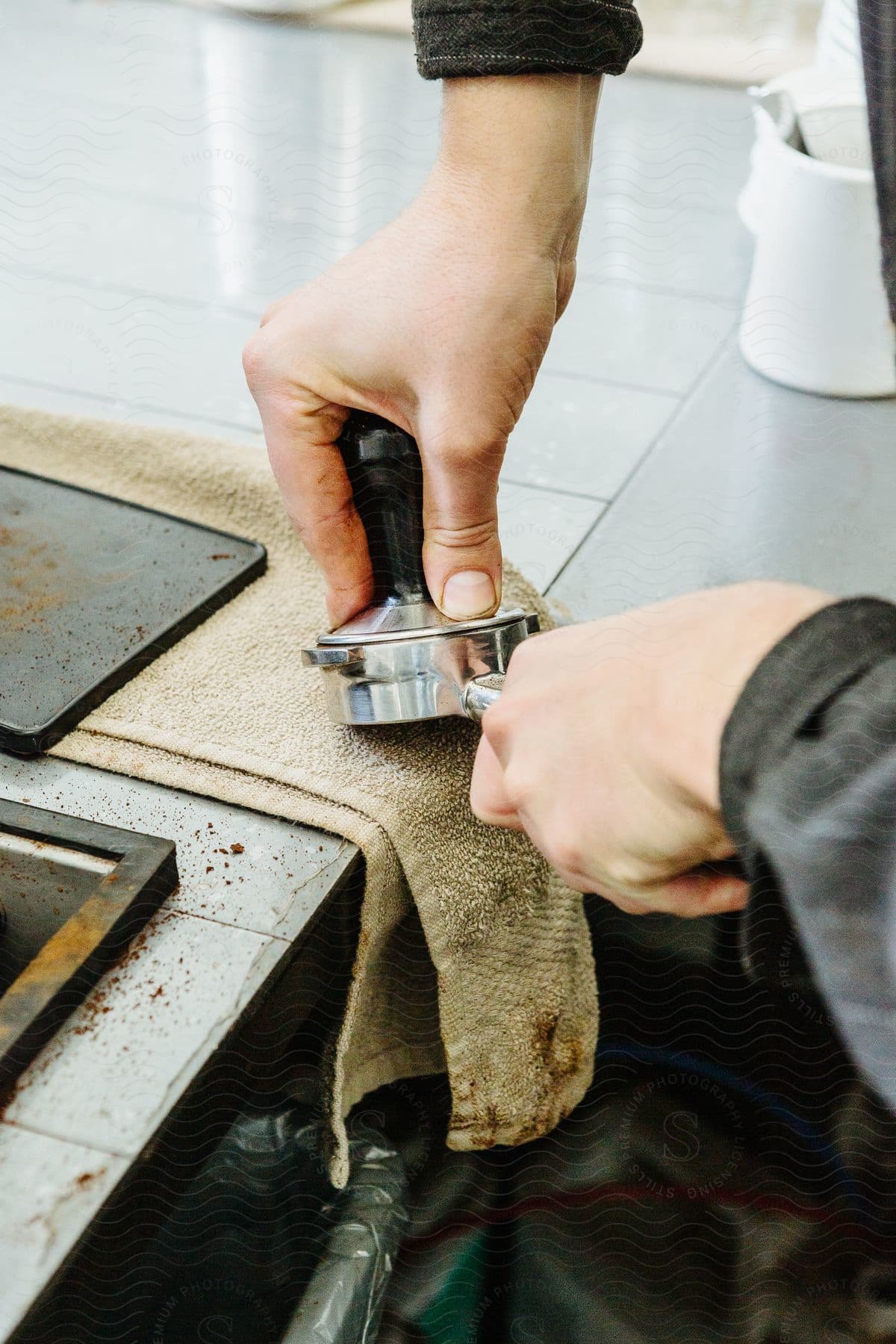 A man holds the handle of a coffee puck as he opens the lid