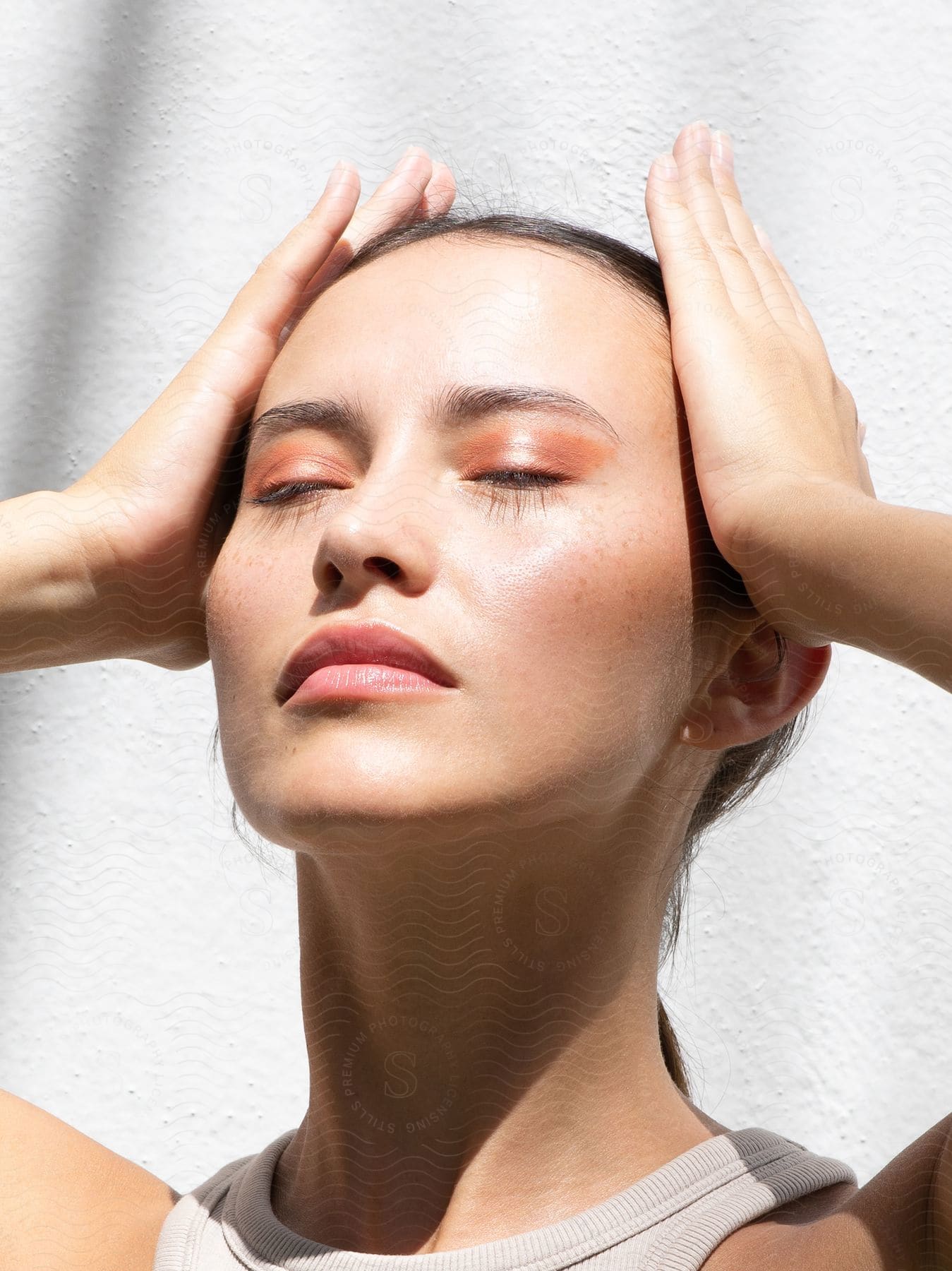 A woman with her hands on her temples and her eyes closed.