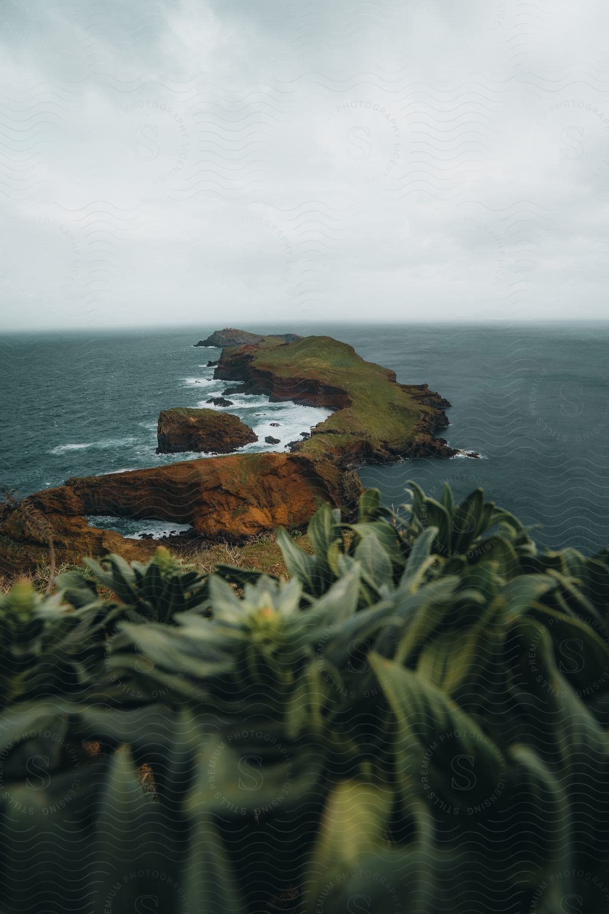 A rocky, verdant island jutting into the ocean under cloudy skies.
