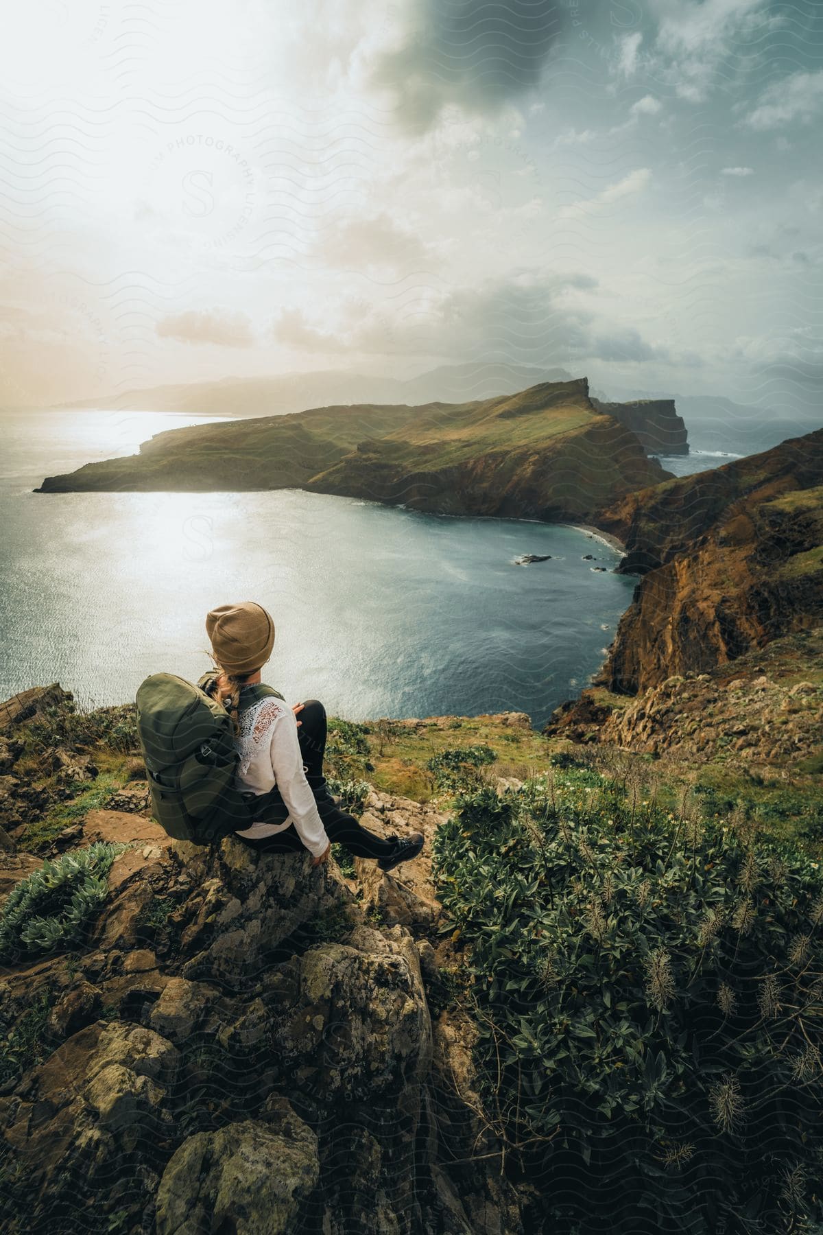 Hiker sitting on a hillside overlooking the water and island