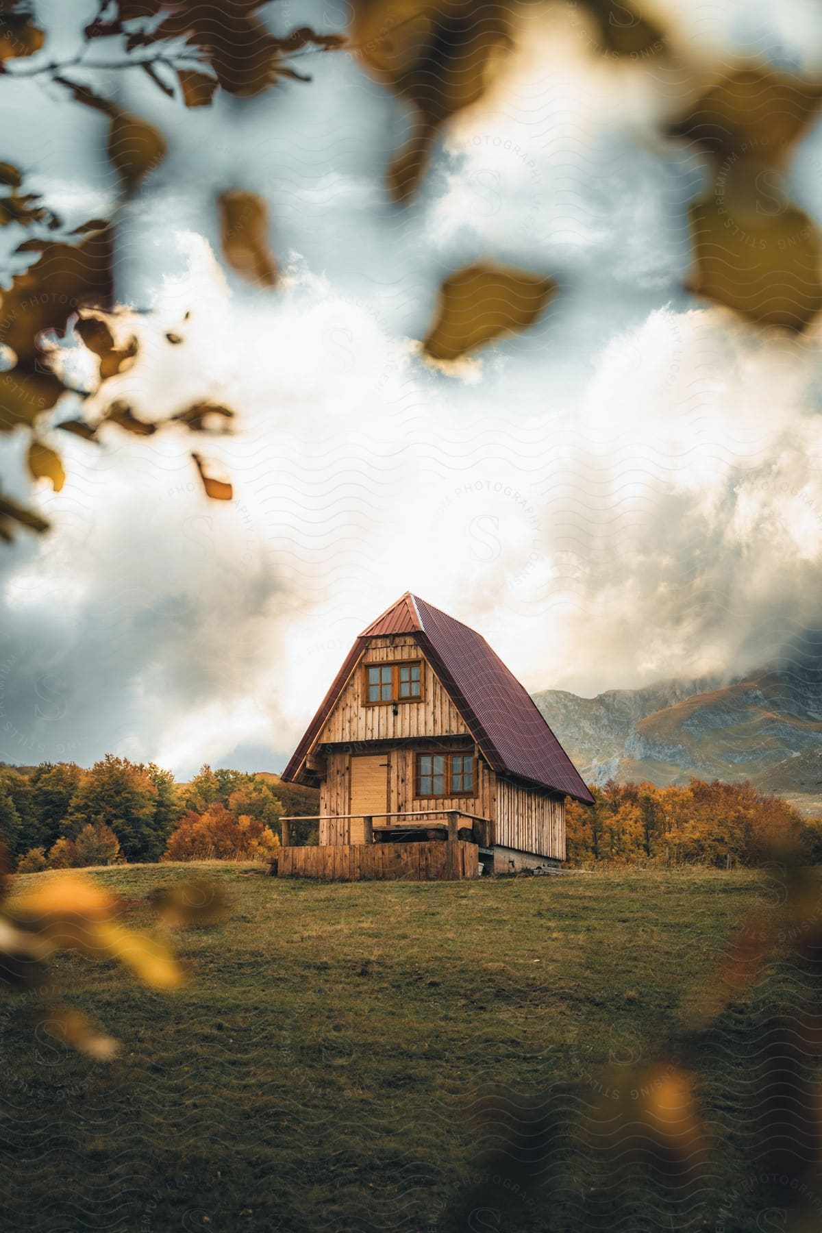 a small wooden house with a red roof in the middle of a green field.