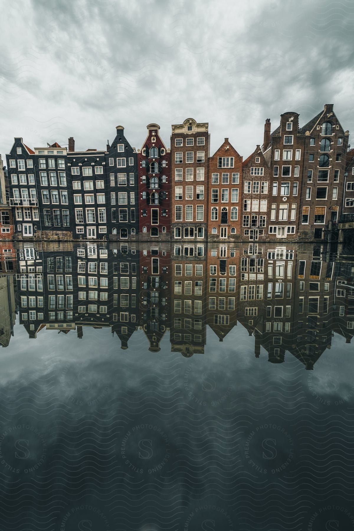 Slim buildings joined together, reflected in the river below them.