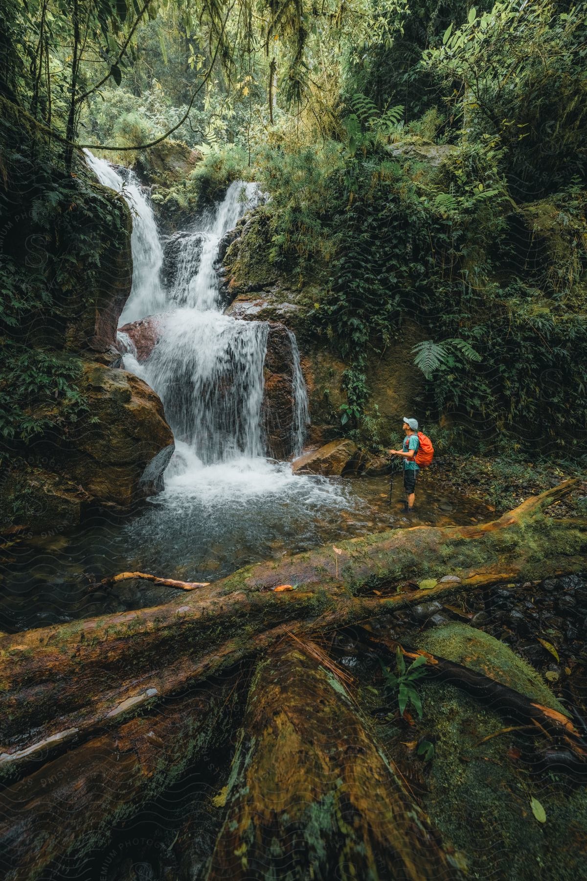 A View Of A Man Hiking Near A Waterfall