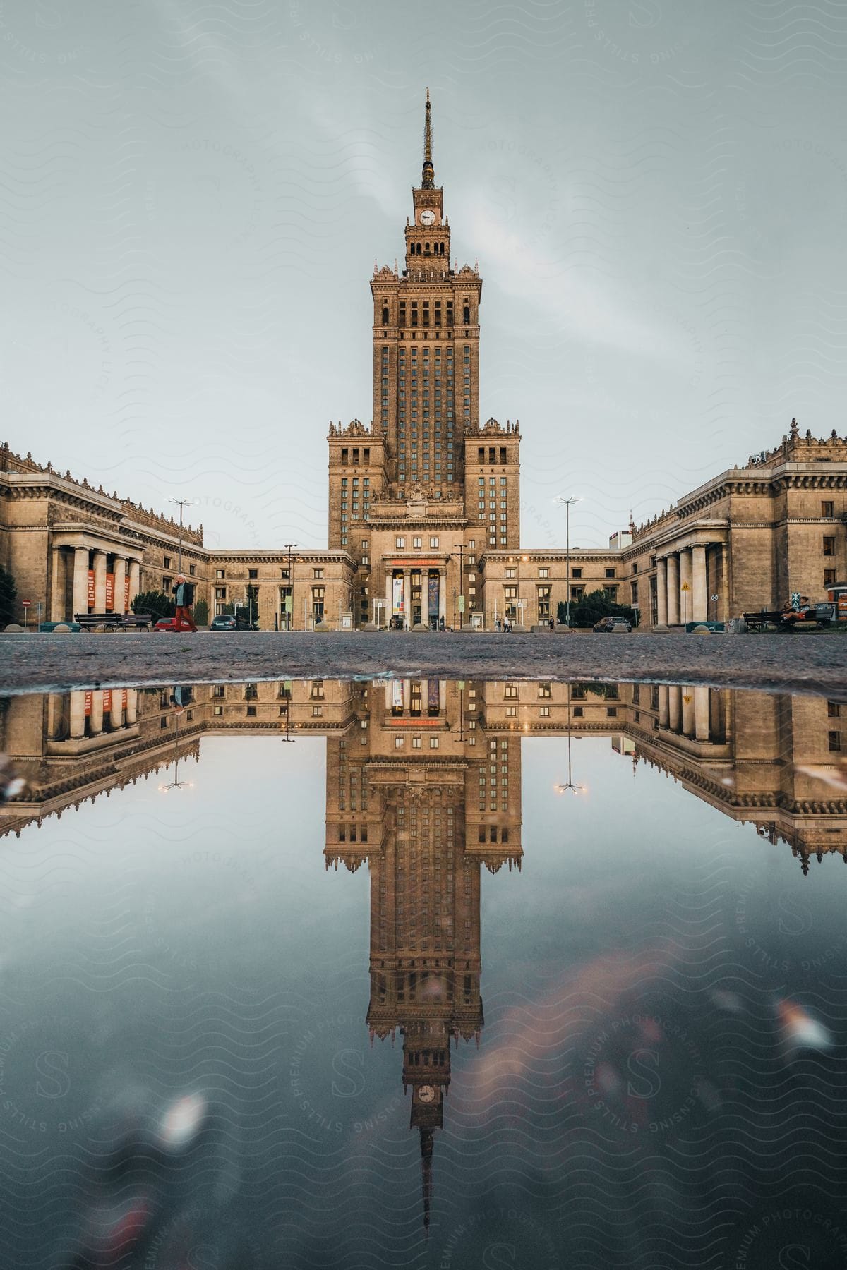 The Palace Of Culture And Science In Warsaw Is Reflected In A Pool Of Water