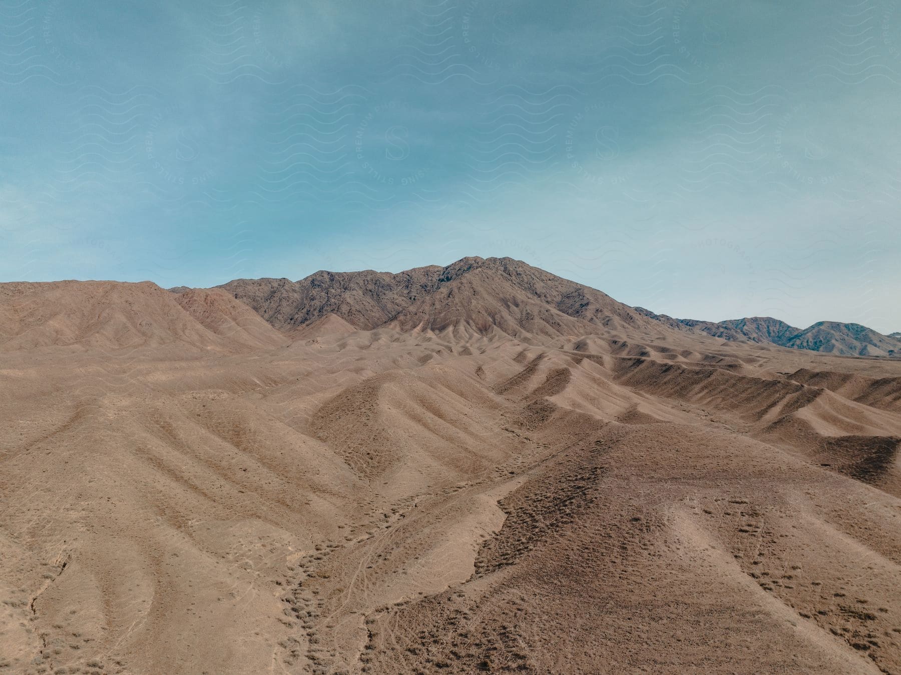 Sand dunes on a desert next to the mountains under a blue sky