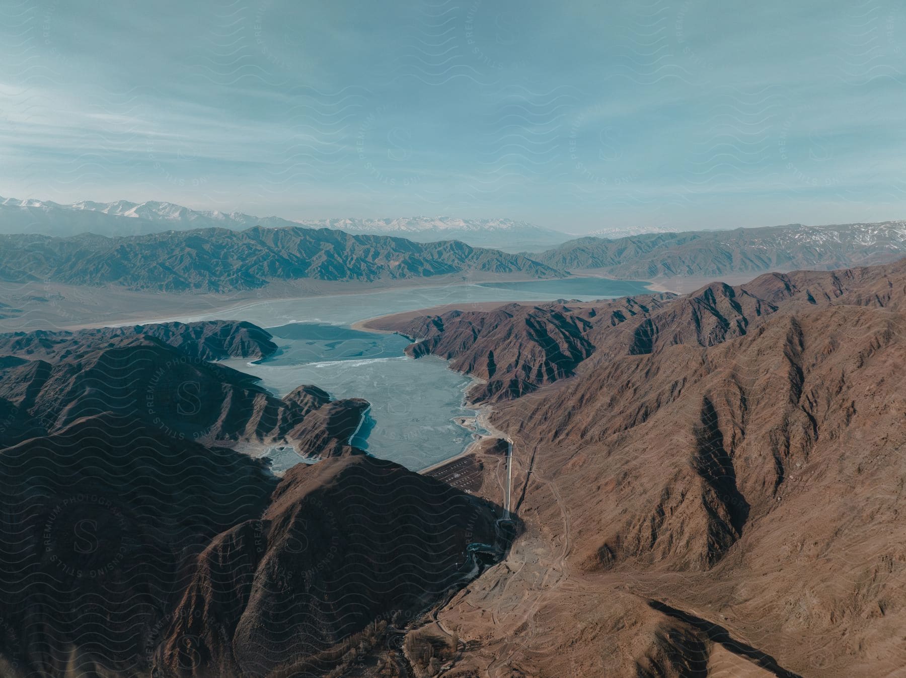 Stock photo of aerial of a river surrounded by mountains in the desert during the day.