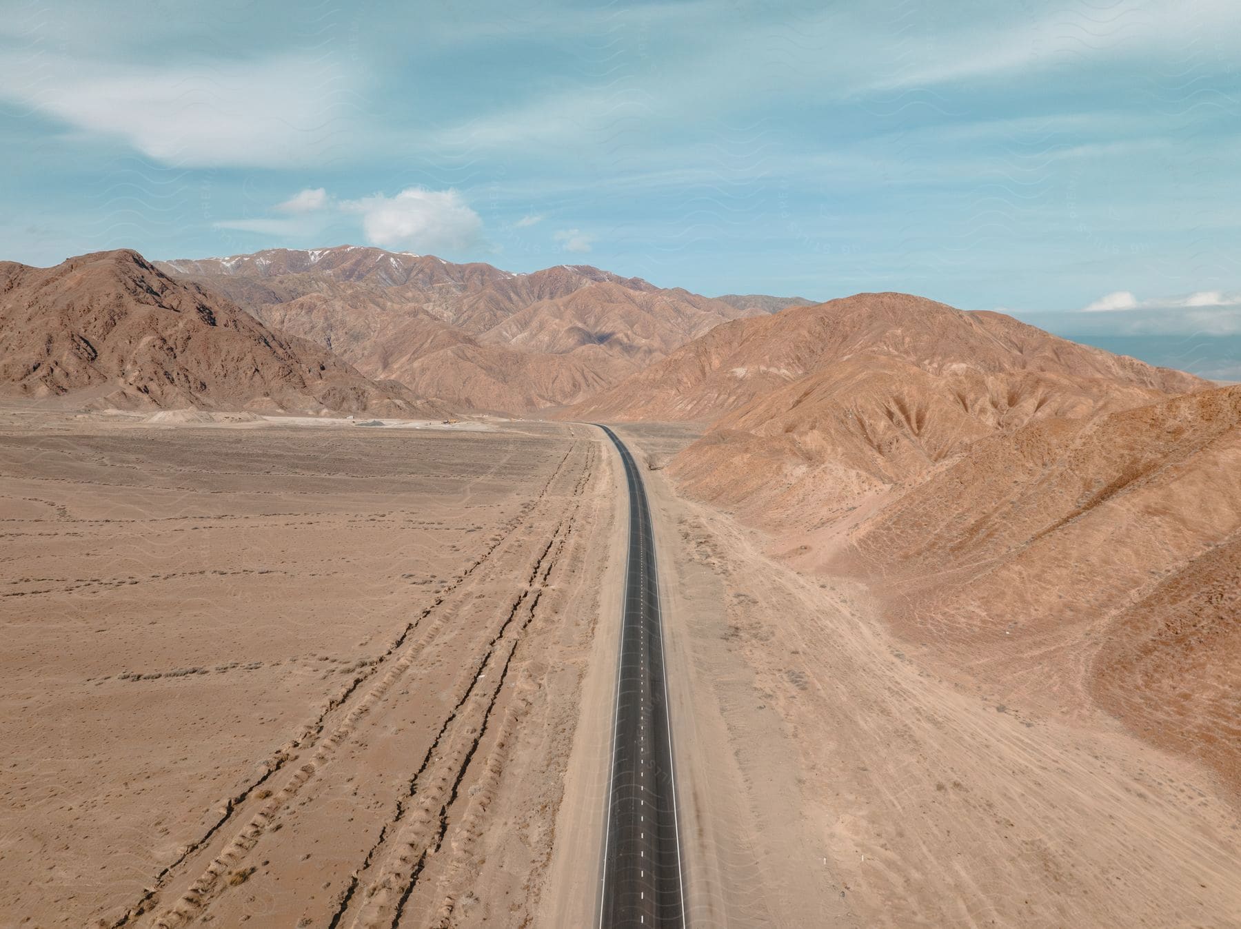 an empty tarred road in a sandy area on a sunny day