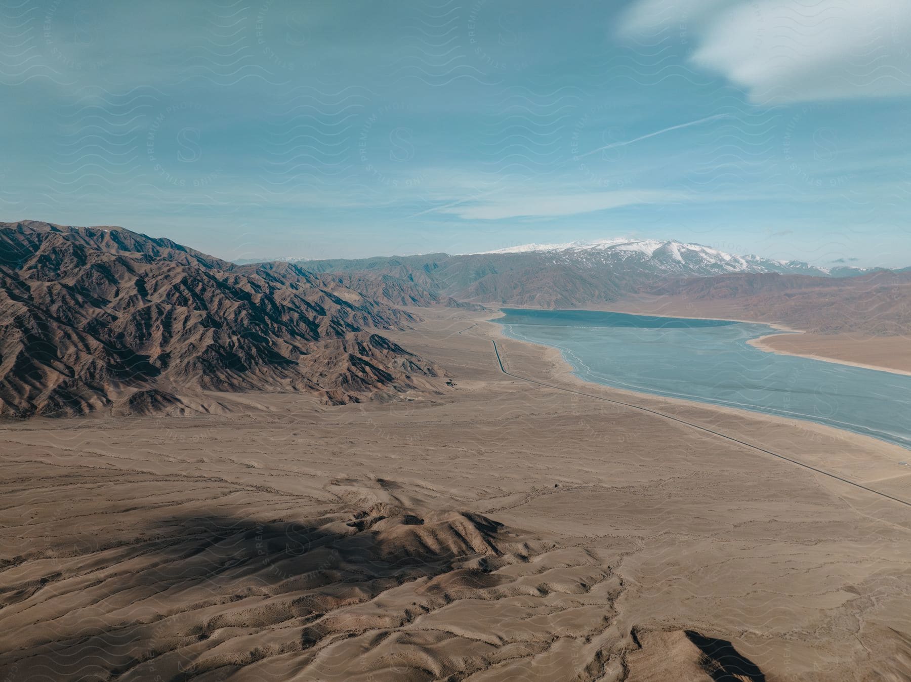 A river runs through the desert with snowy mountains in the distance.