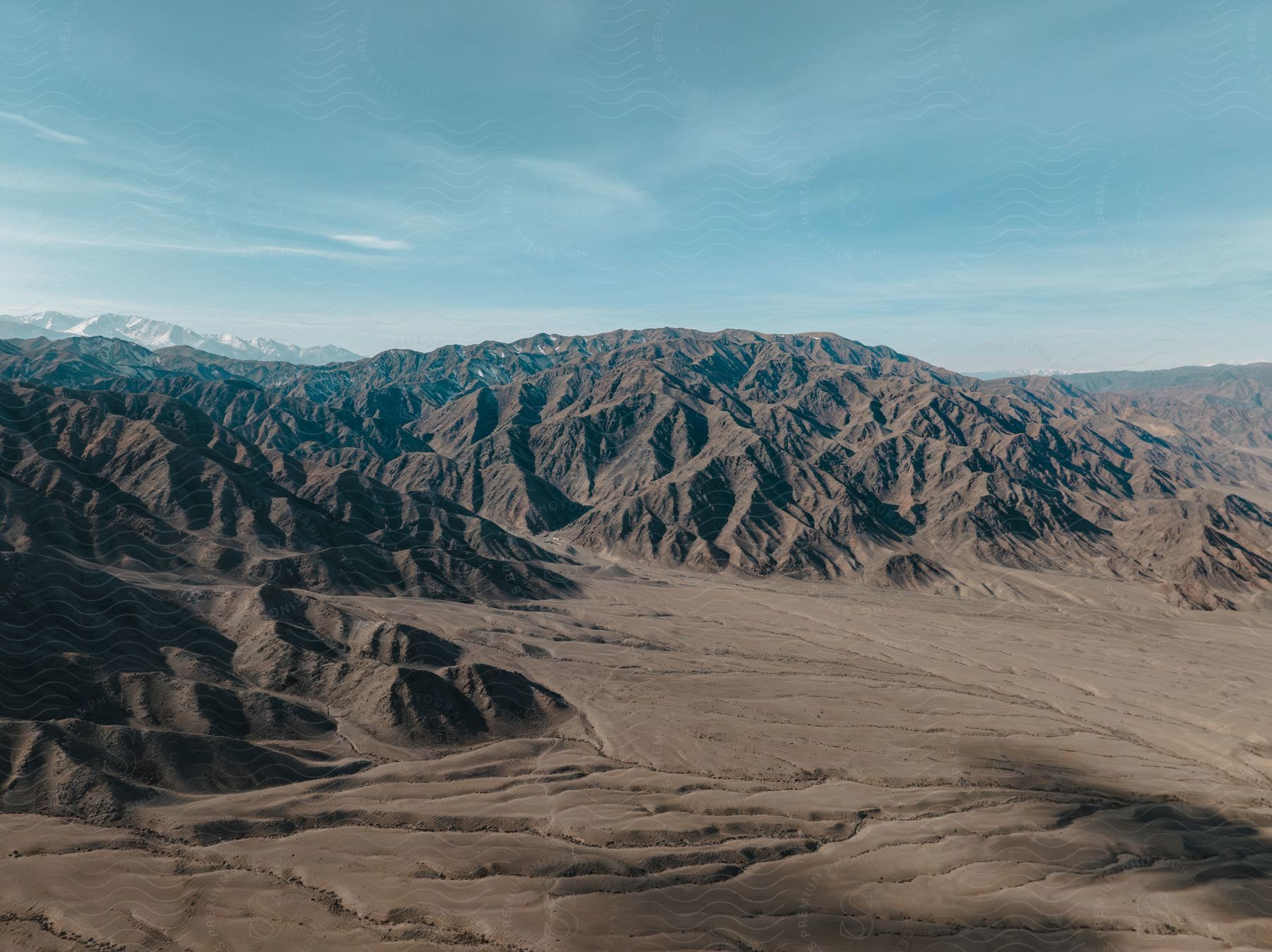 Panorama of clay soil with rocky mountain ranges on a blue sky day with few clouds