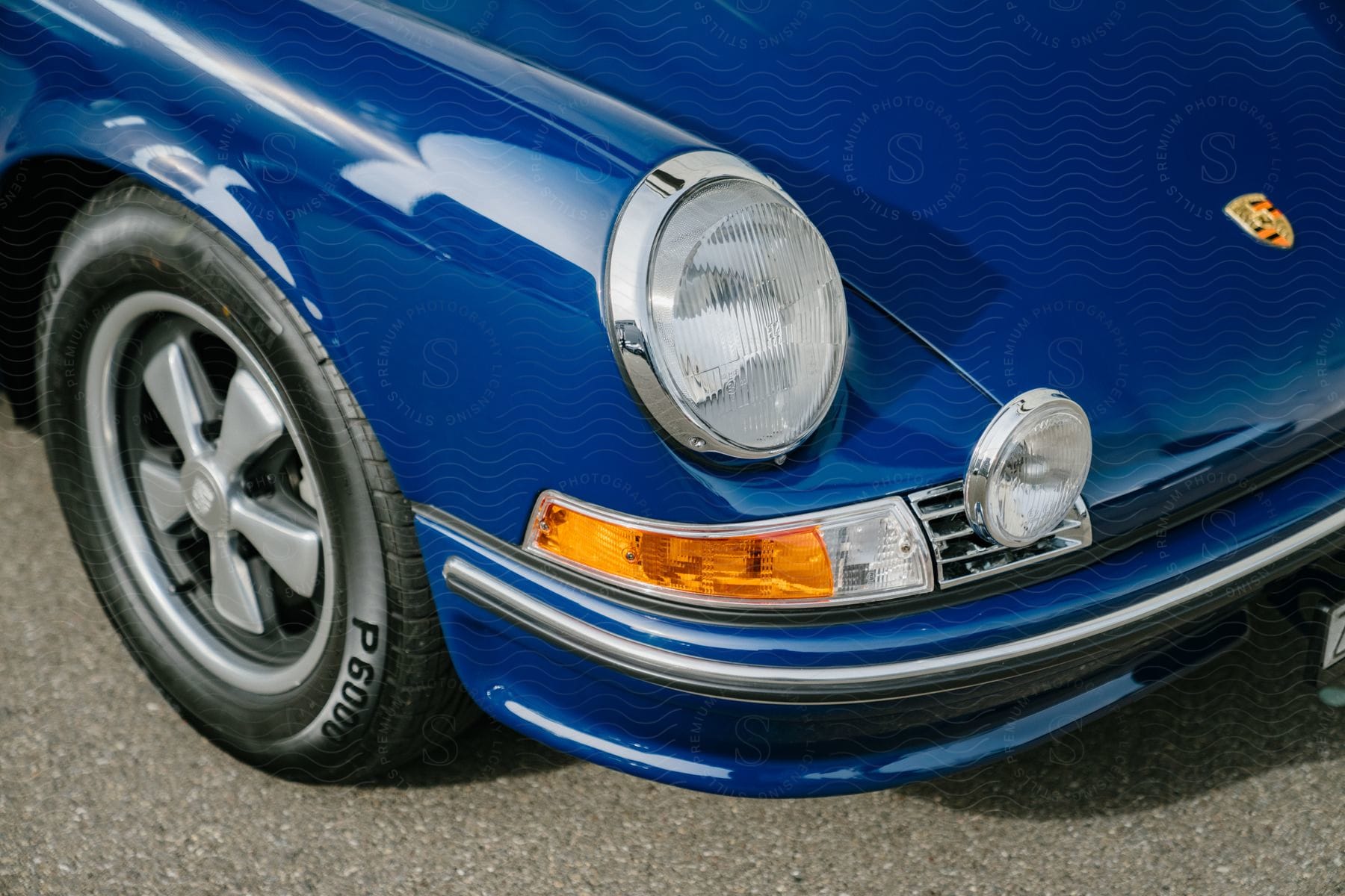 Close-up of the hood and headlight of a royal blue sports car.