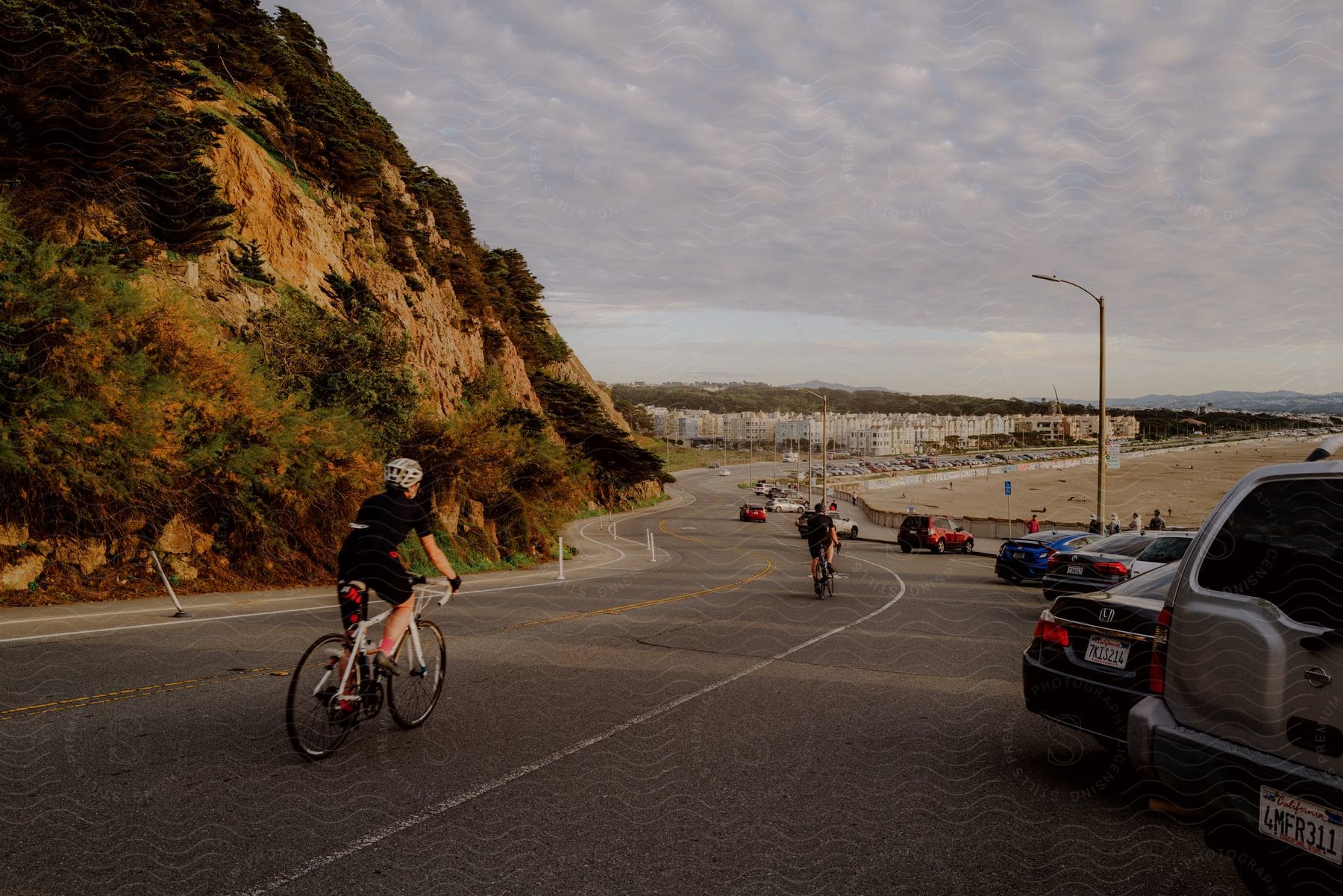 People ride bicycles along the beach during sunset.