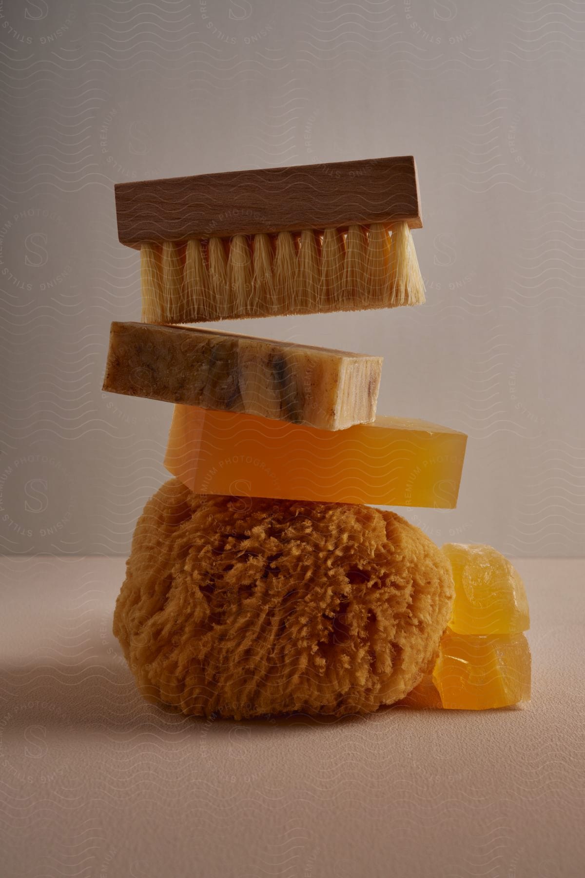 Brush And Sponge Are Stacked With Different Soaps Against A Gray Background