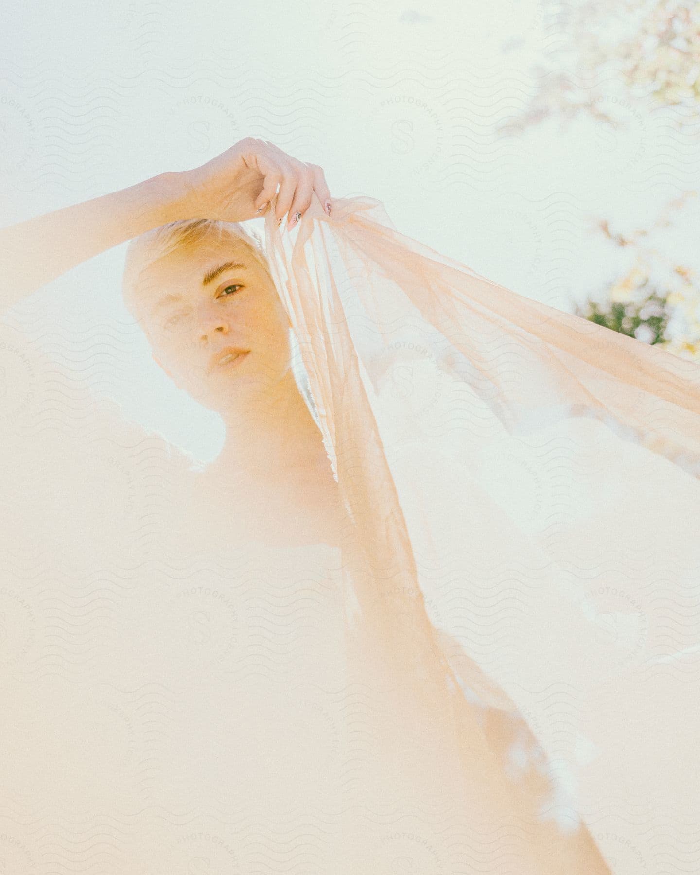 Blonde woman holds fabric panel on bright sunny day.