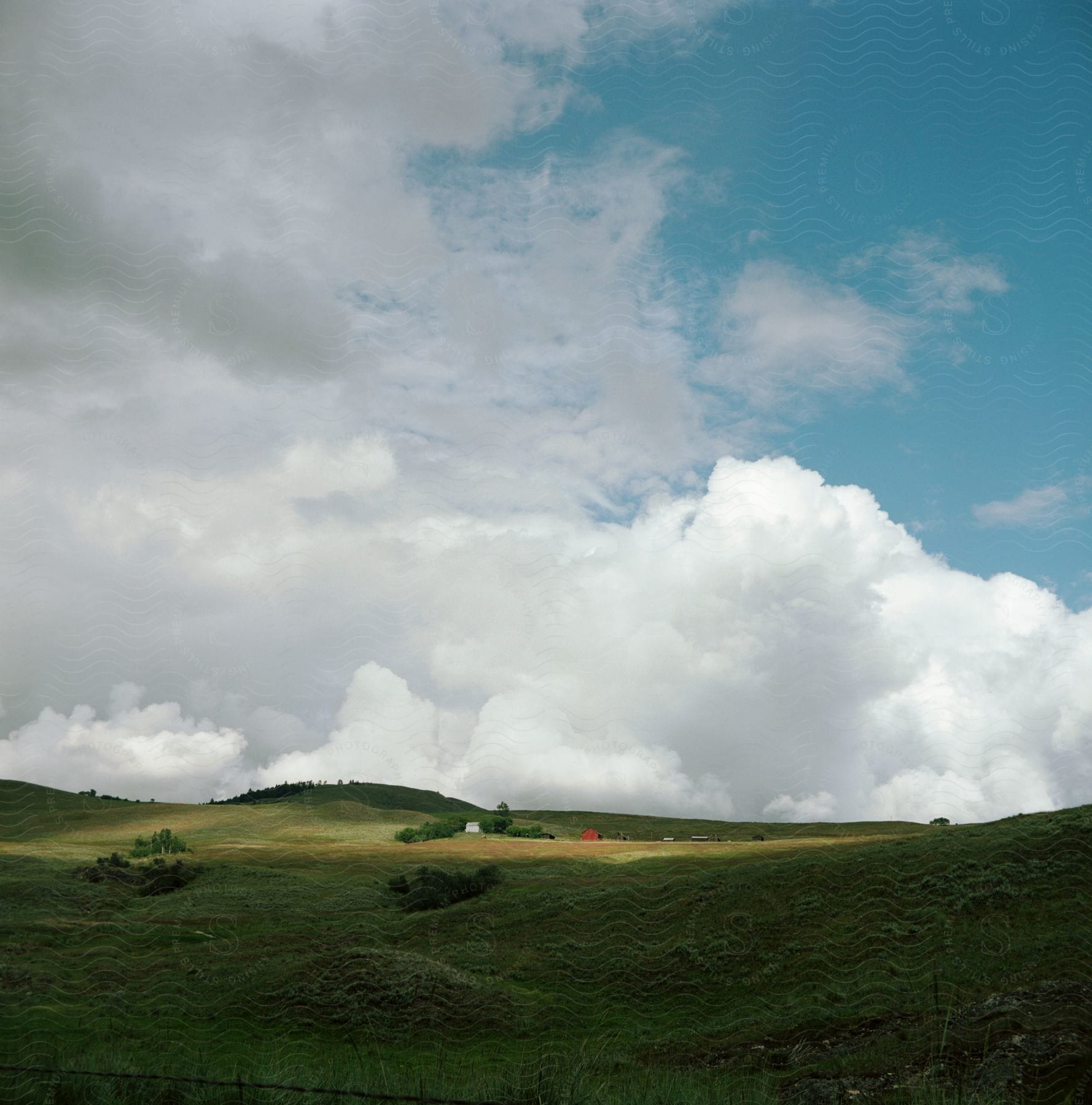 Cumulus clouds and blue sky above a green Hillside