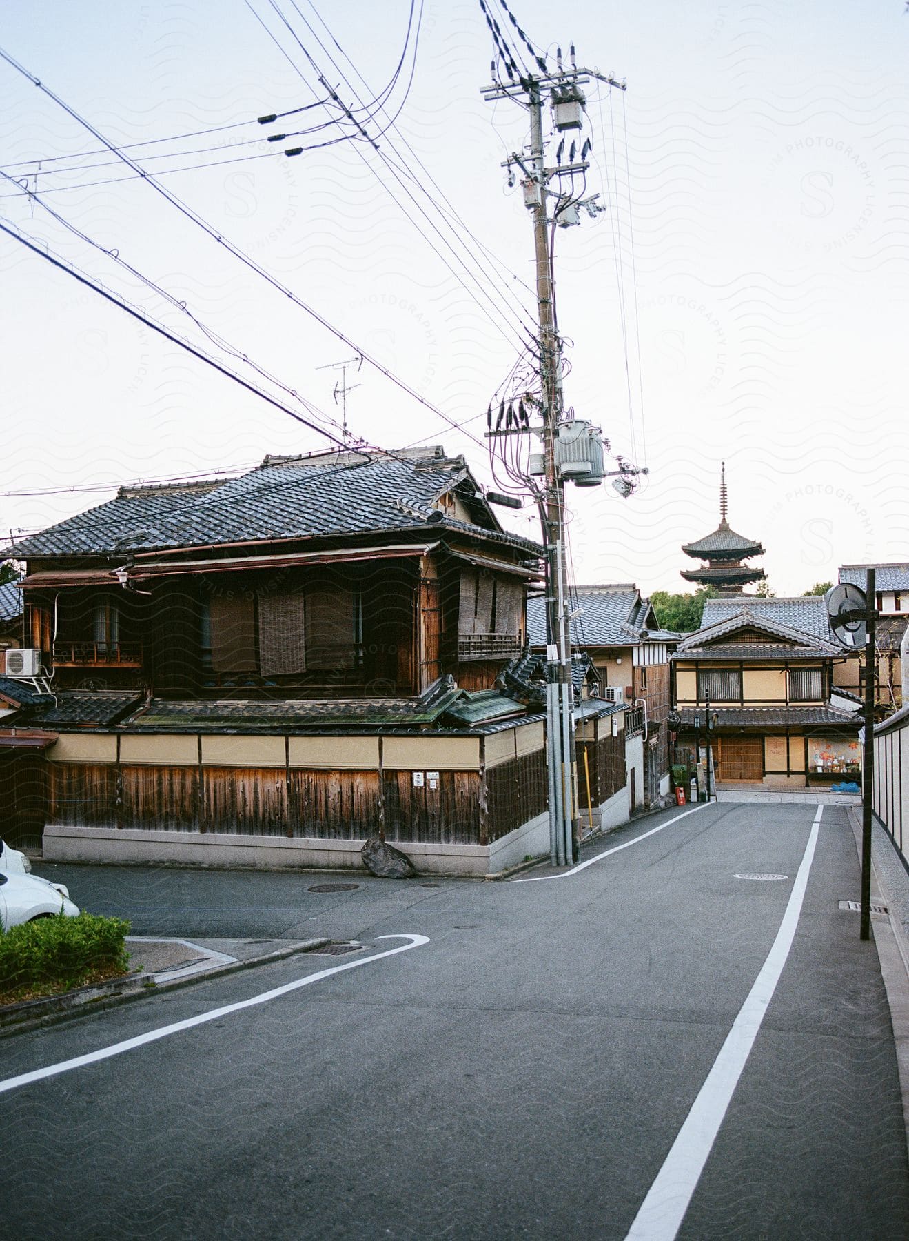 A quiet street scene with traditional Japanese wooden houses and a pagoda in the background.