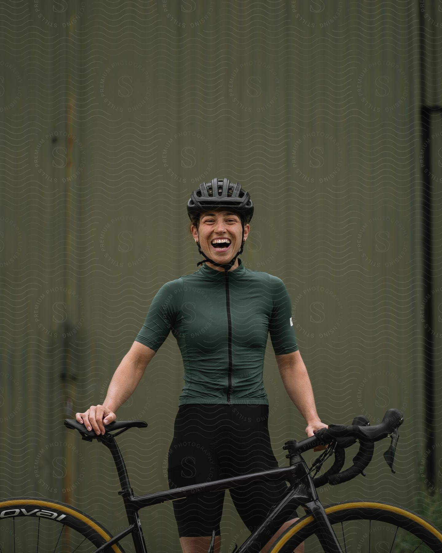 Smiling woman with cycling equipment in front holding her bicycle