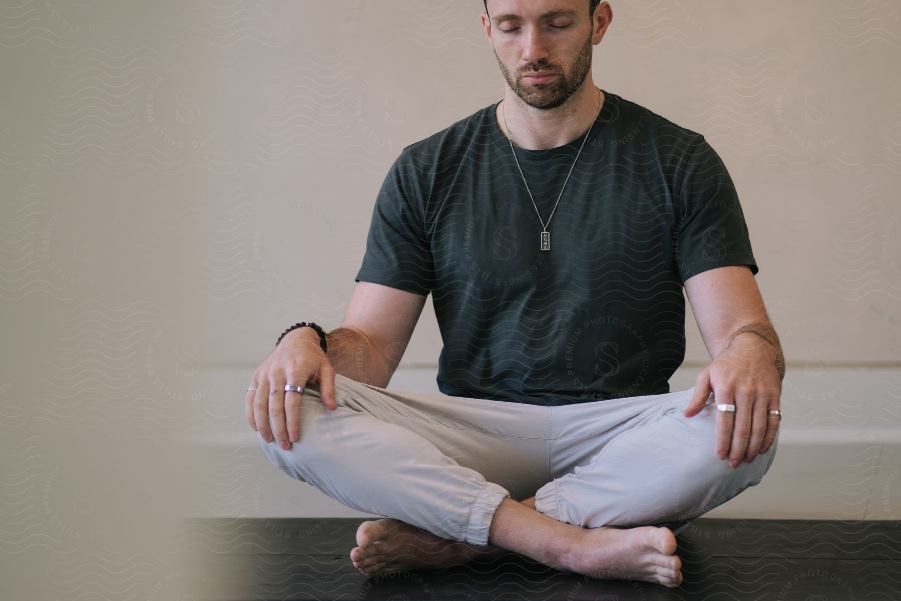 A man is sitting and his hands are on his knees and he has his eyes closed while doing yoga