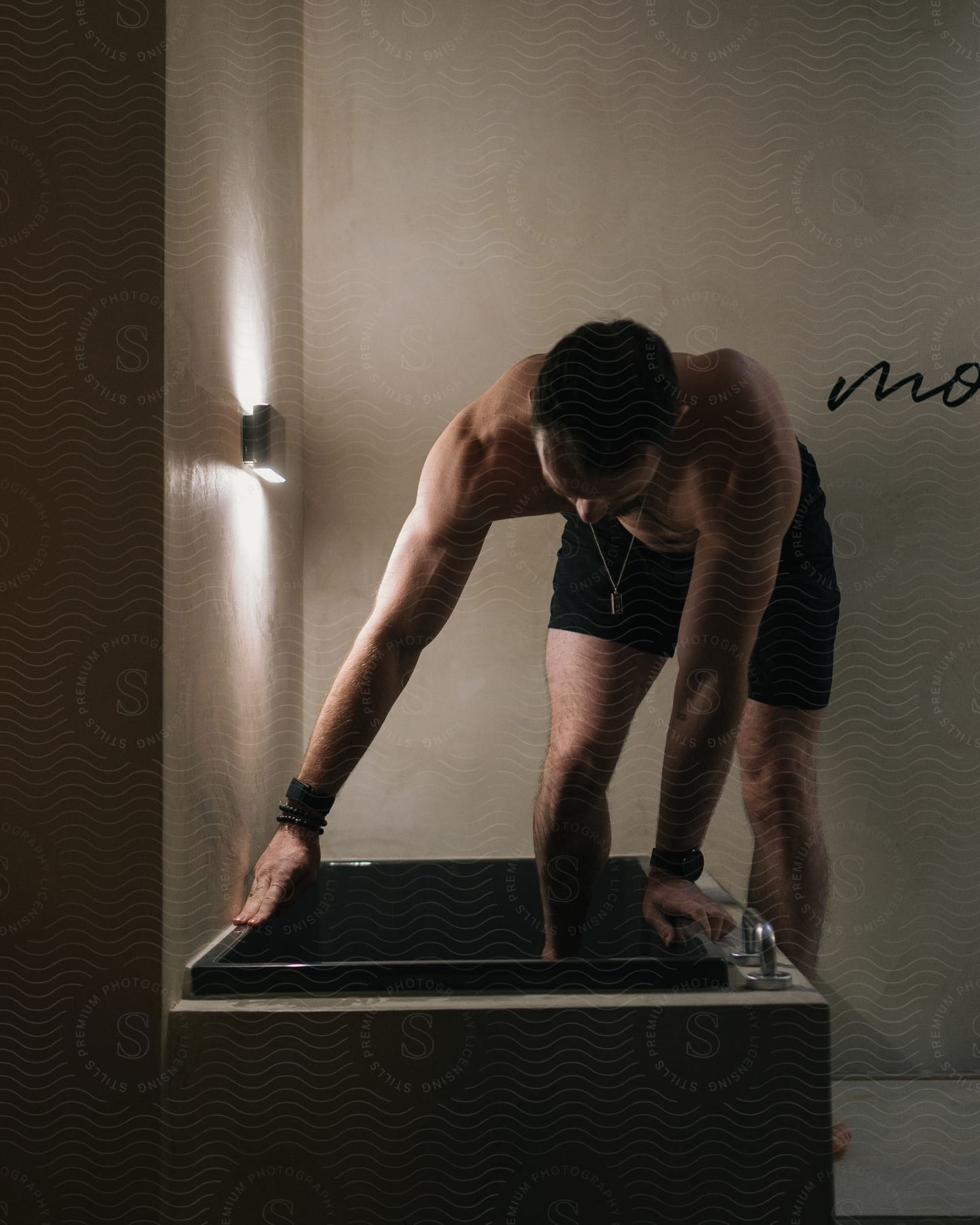 A man holds the sides of a bathtub as he exercises