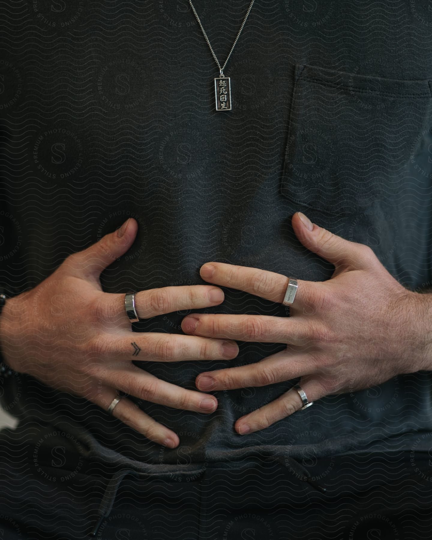 Two human hands full of ring on the belly of a person who is wearing black shirt