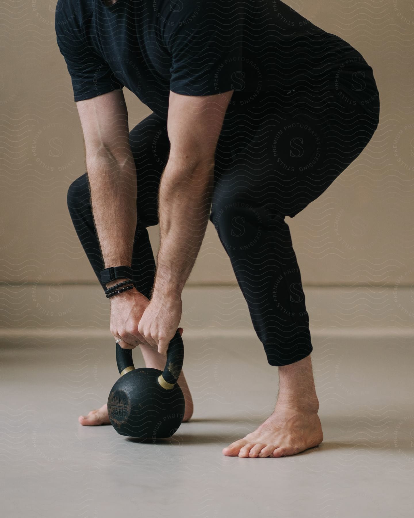 The person is squatting holding a kettlebell close to the floor.