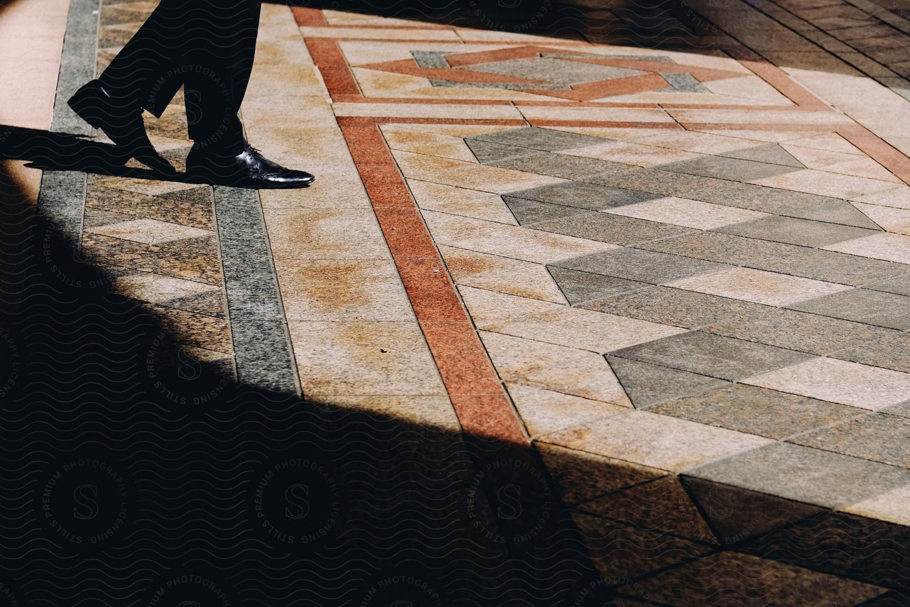 A person walking on tiled floor partially lit by sunlight.