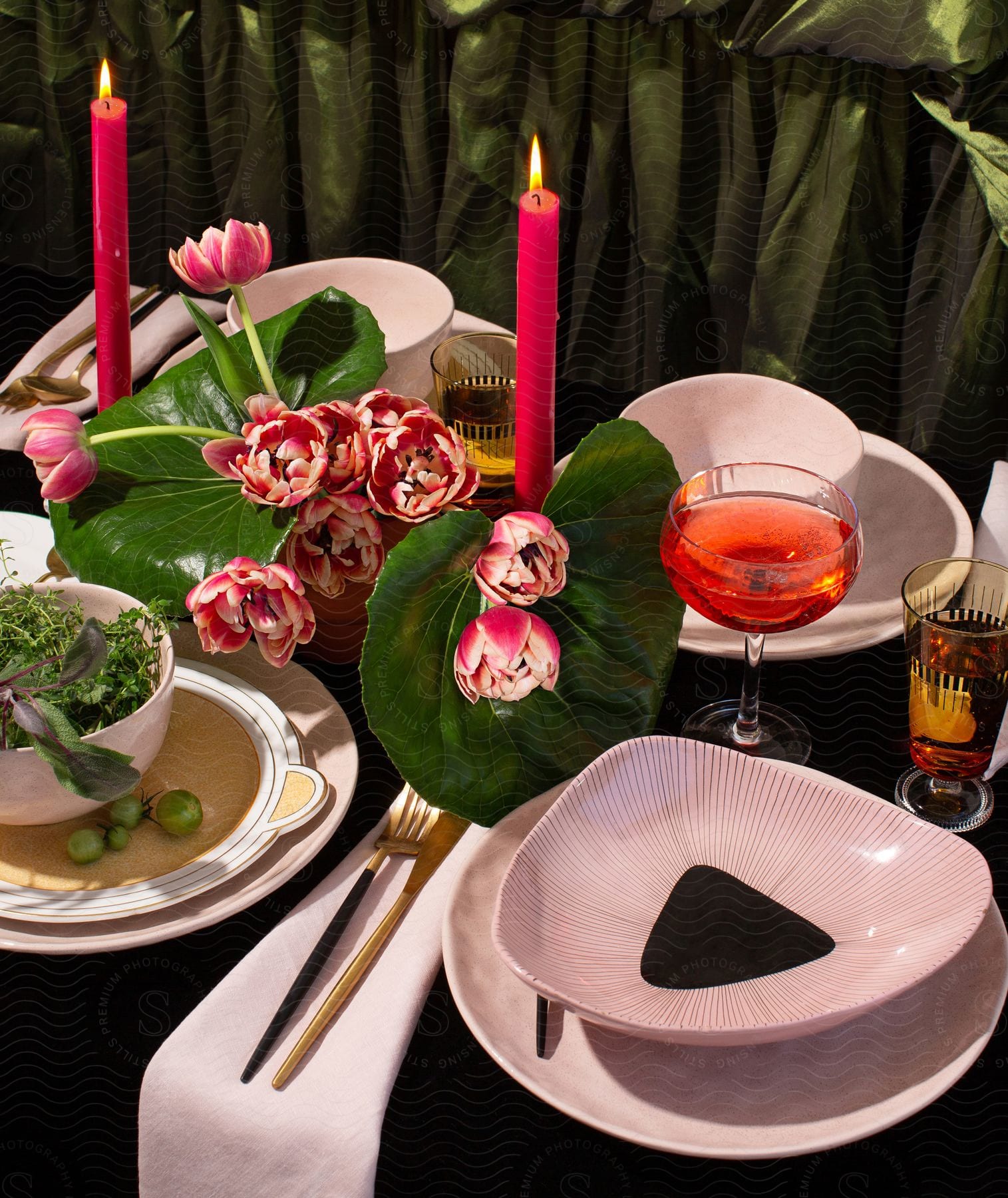 Stock photo of pink flowers flanked by large green leaves in the center of a table set for four.