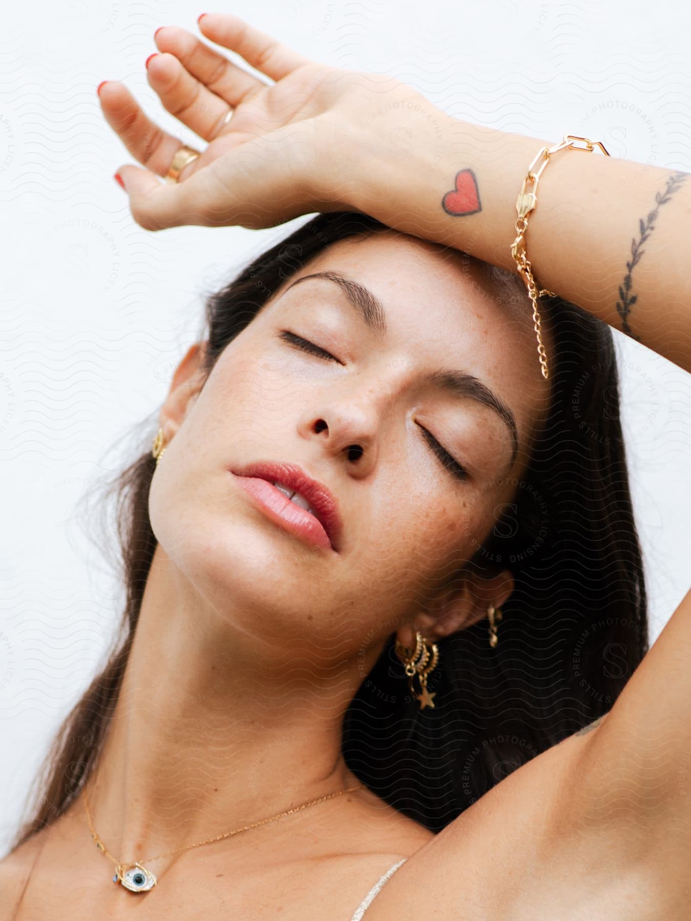 A woman models a bracelet and other jewelry with her arm up and resting on her forehead