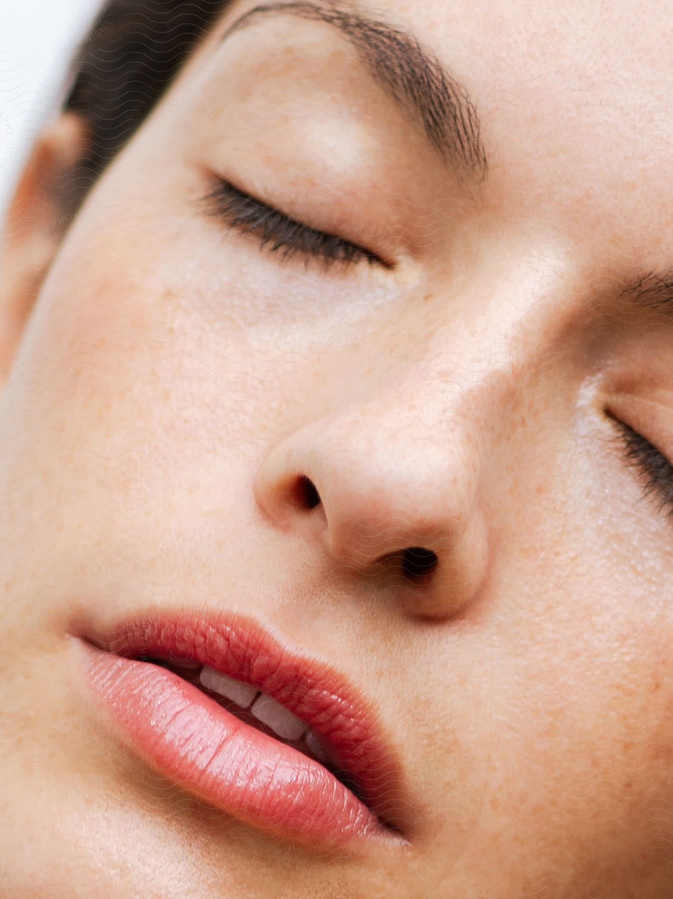 A woman's face with her eyes closed and her lips are open showing some of her teeth