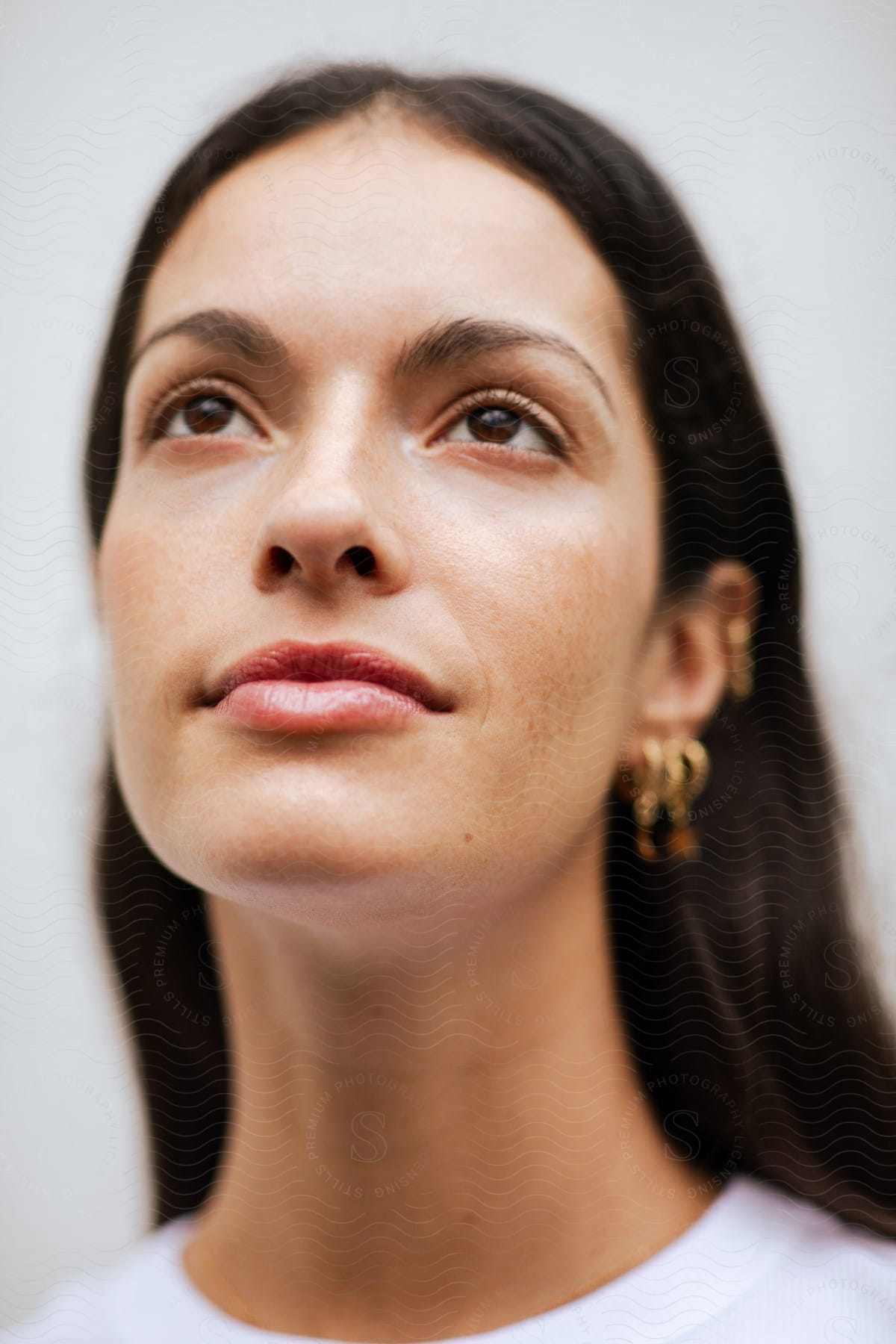 Close-up of a beautiful woman's face wearing gold jewelry.