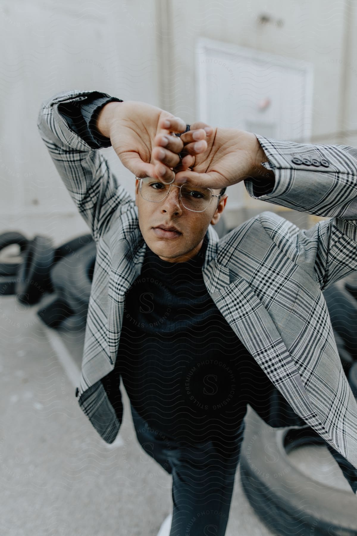 A man wearing a black and white plaid blazer holds his hands by his forehead