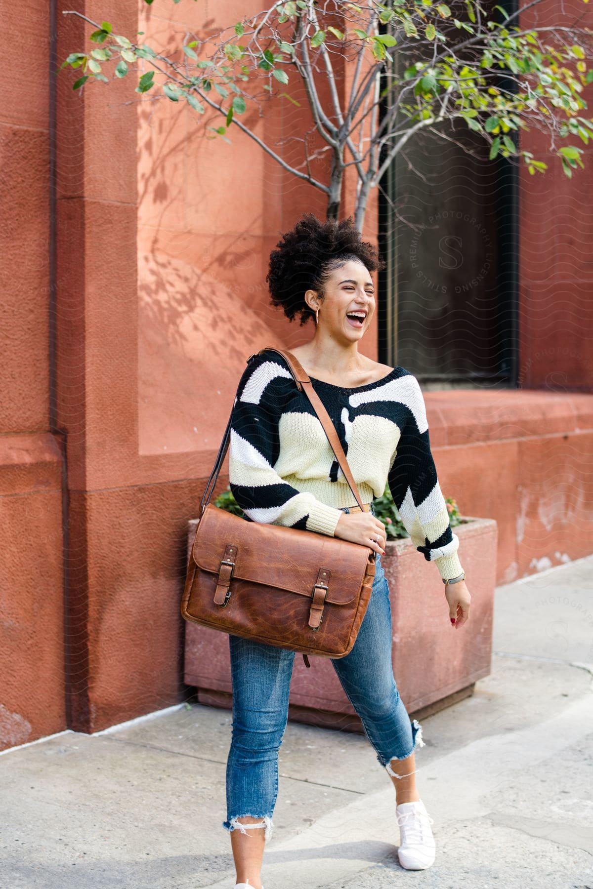 A woman modeling some clothes and a bag outdoors