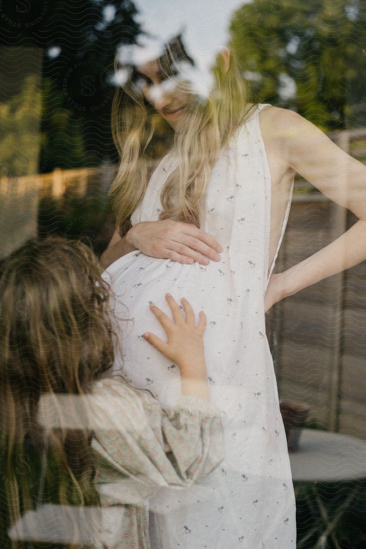 A child kissing a pregnant woman's belly.