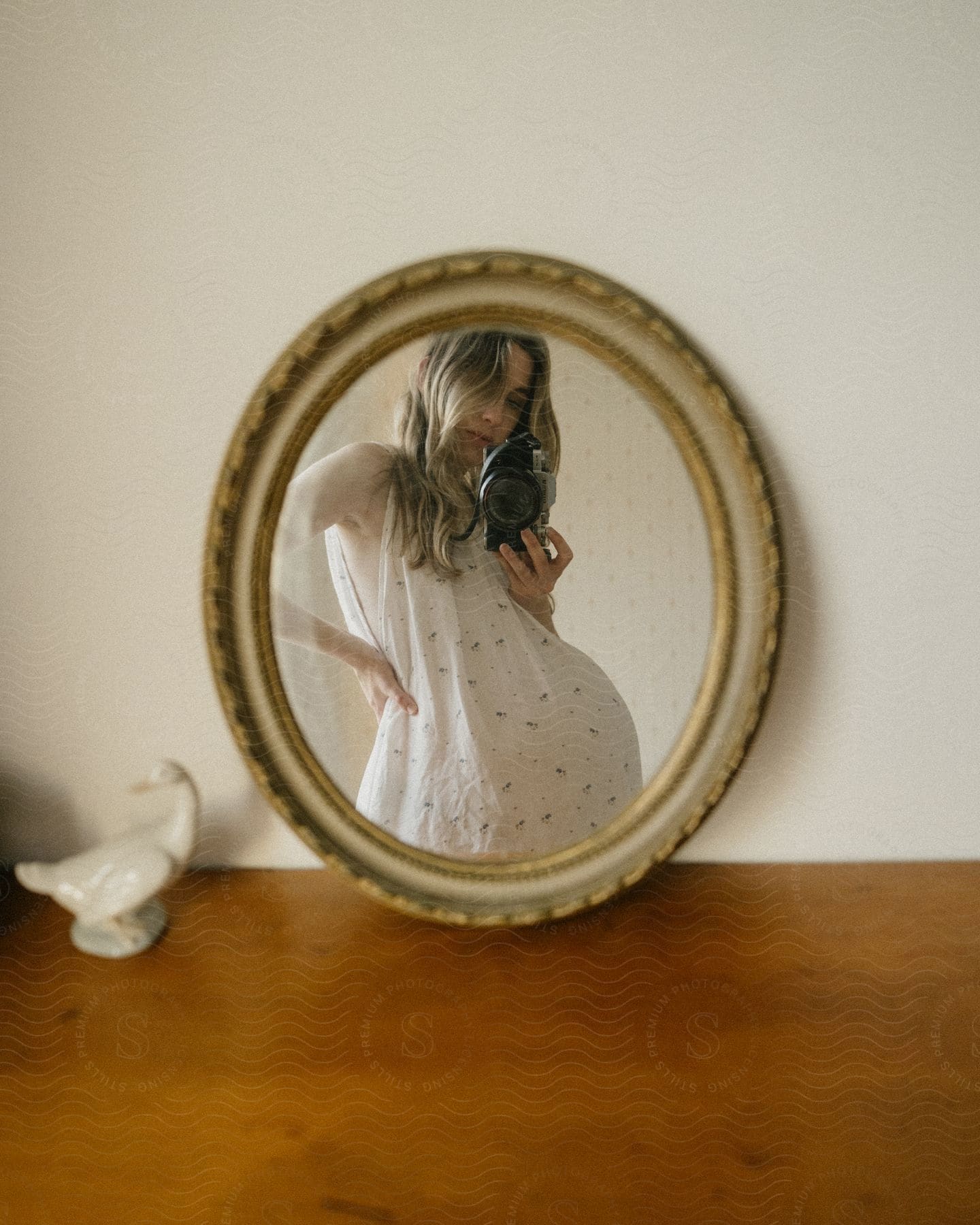 A pregnant woman taking a photo in a mirror.