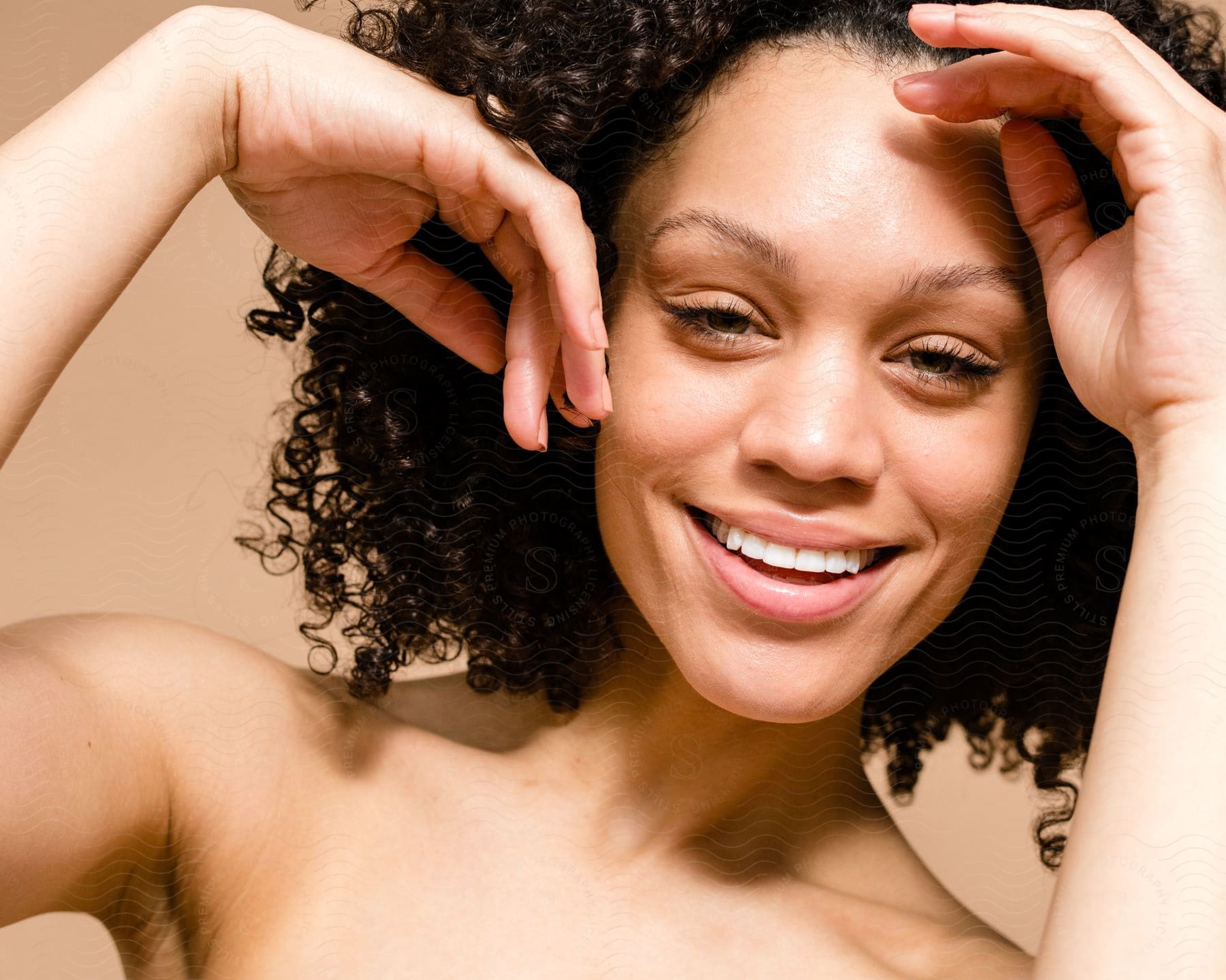 Portrait of a half-naked smiling young woman with her black curly hair