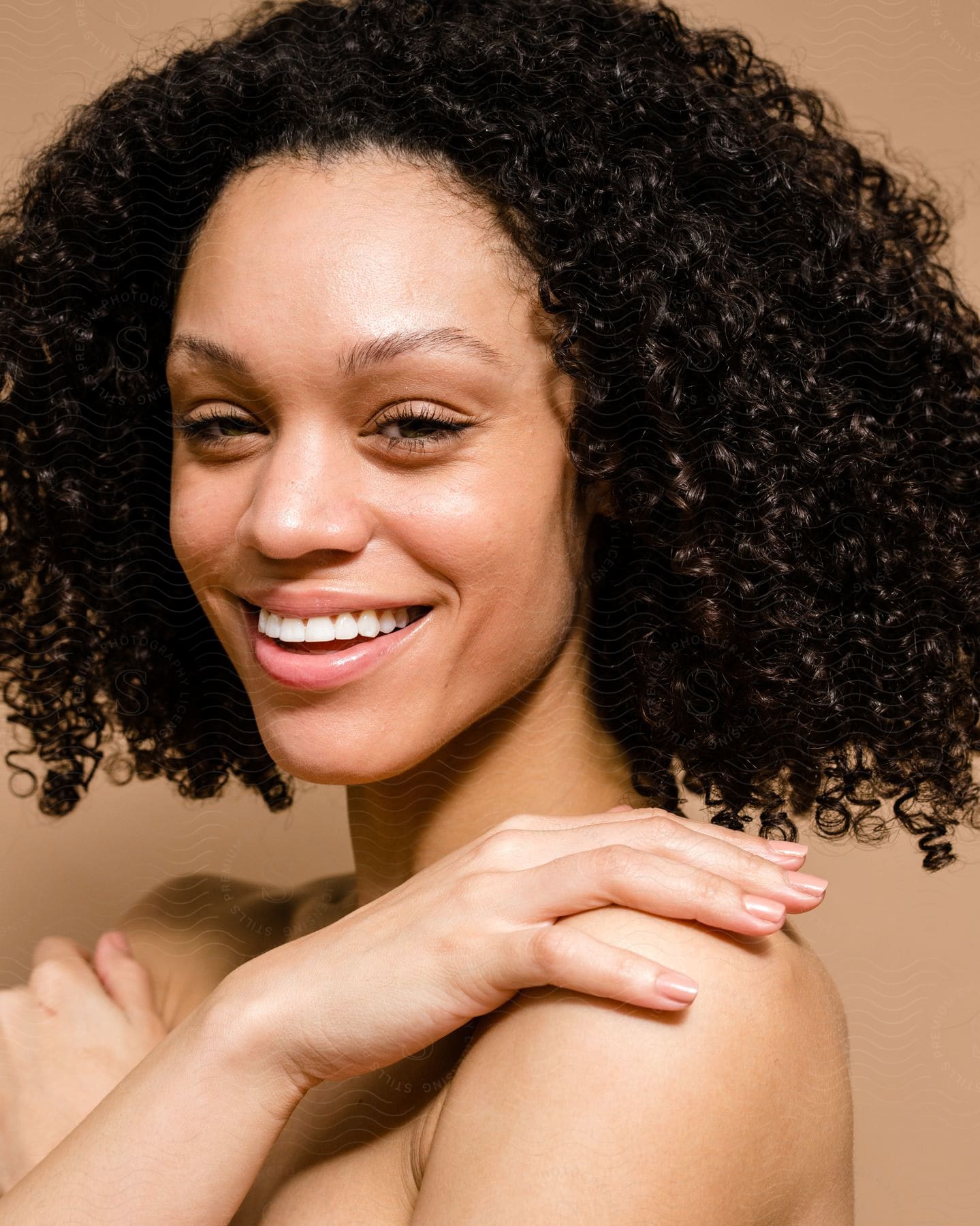 A beautiful black woman smiling big with arms crossed over her bare chest and shoulders