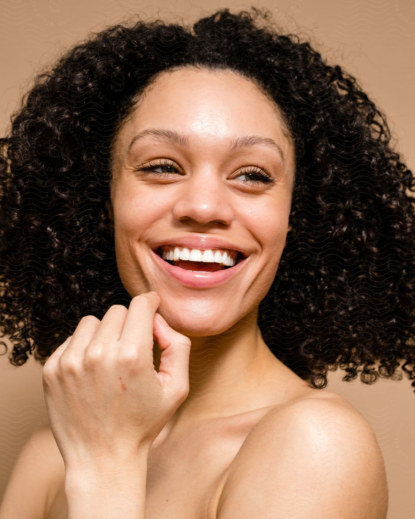 Close up of woman with shoulder length curly hair smiling.