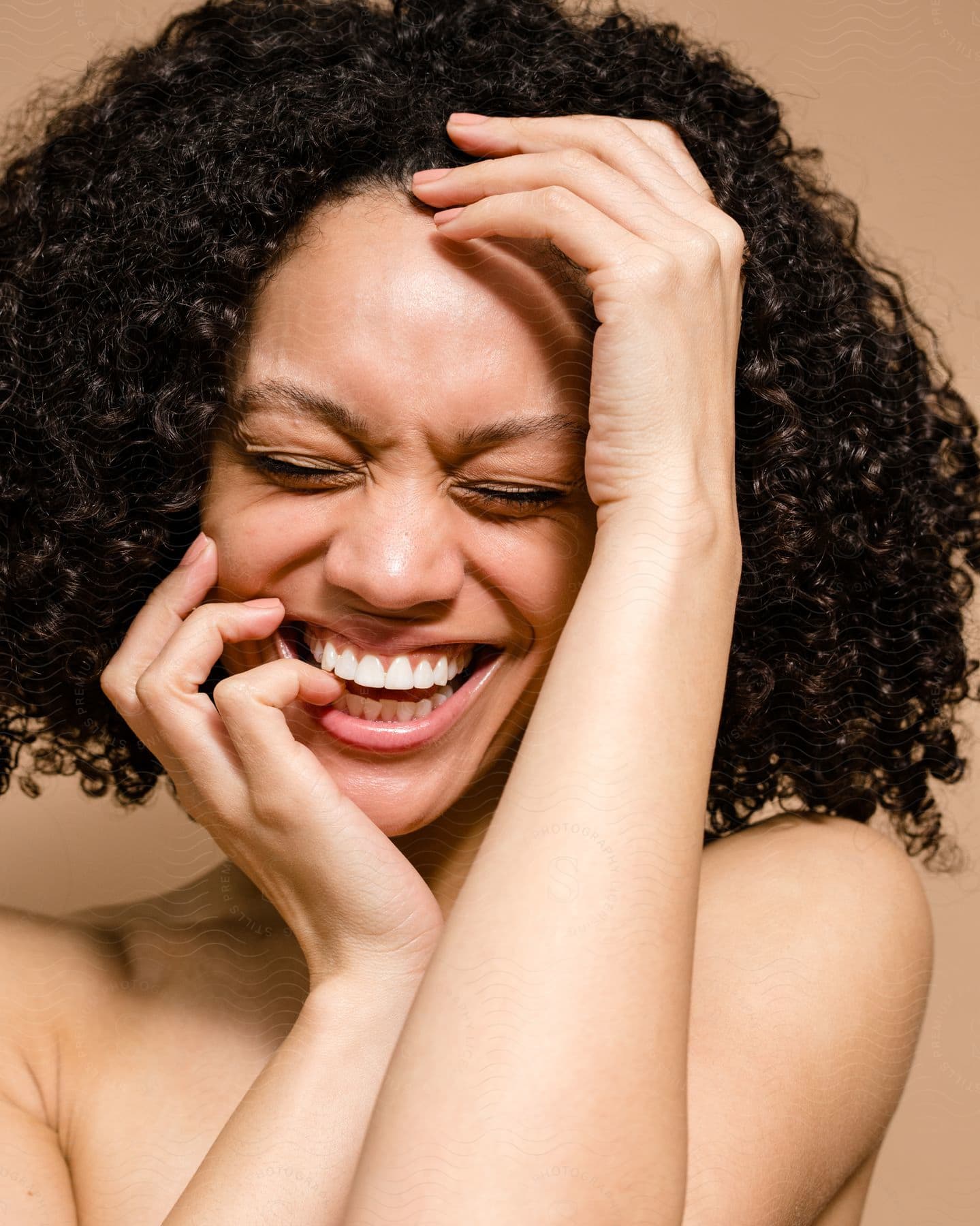 Woman is laughing with one head above her forehead and the other on her chin with fingers near her mouth