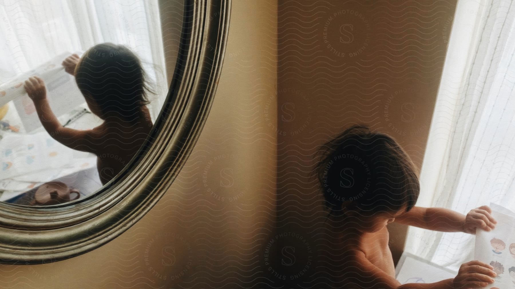 Toddler playing in the bathroom reflects in the round mirror