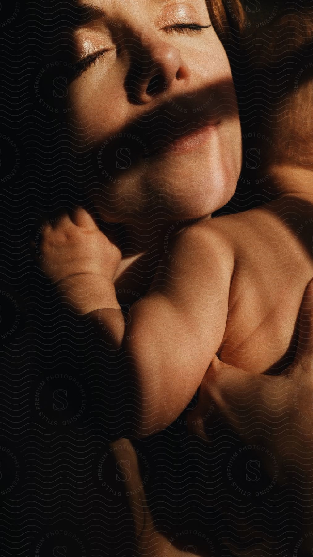 Close-up of a woman's serene face hugging a baby.