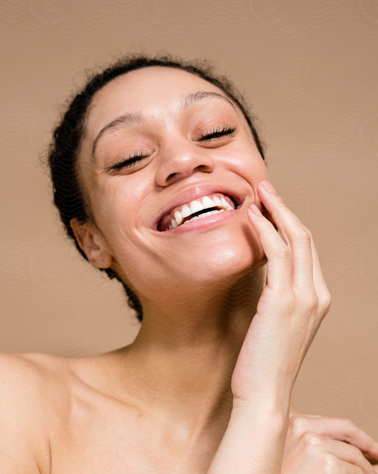 A smiling woman with a hand touching her face.