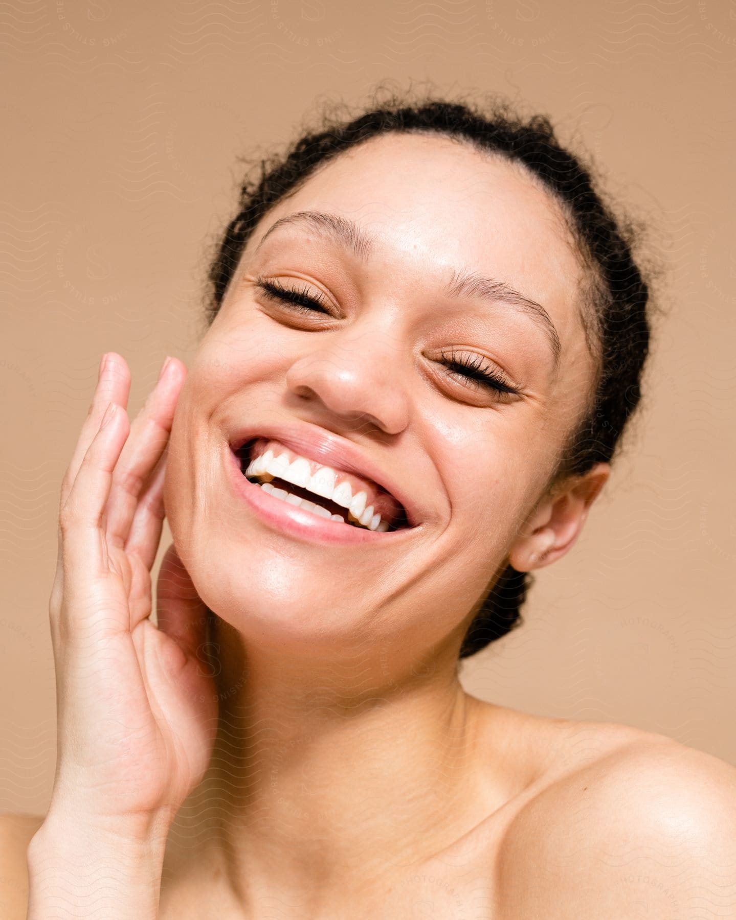 Portrait of a young smiling woman with one of her palms on her face on a blurred background