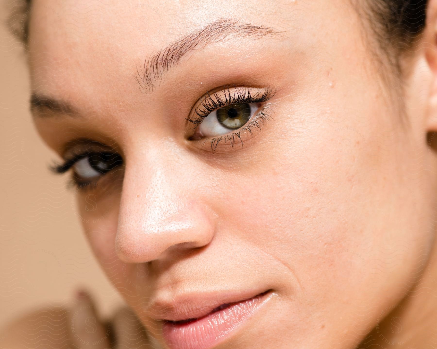 Close-up of a woman's face with greenish eyes and her eyelashes with mascara highlighted on a blurred background