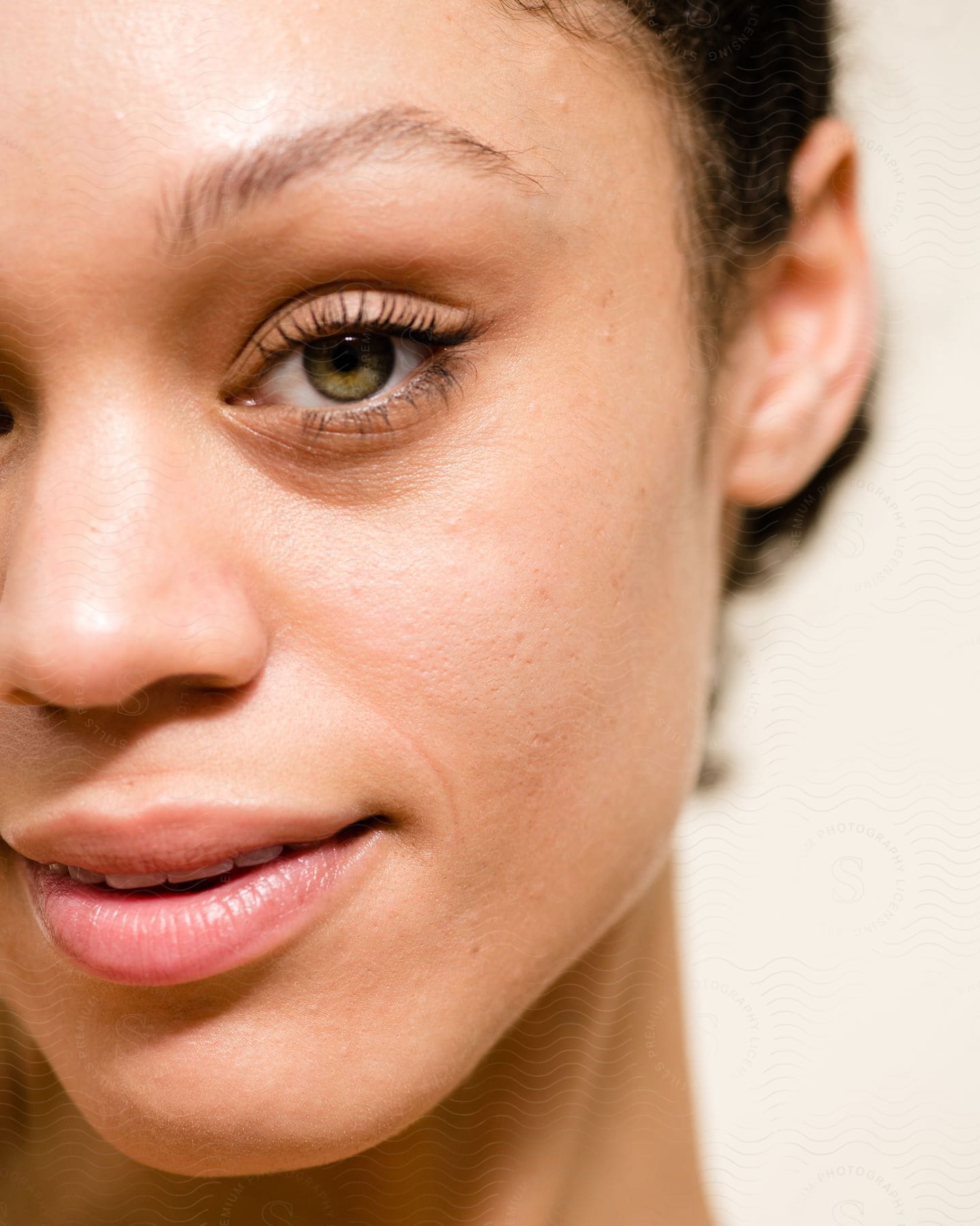 Partial portrait of a young woman with green eyes and her black hair tied up on a white blurred background